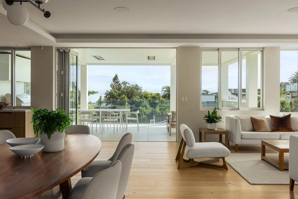 Daylight fills the dining and living spaces at 20 Springcombe Road, St Heliers, Auckland, drawing the eye towards the balcony and coastal outlook beyond. Expansive openings create an effortless connection between interior and exterior, bringing light