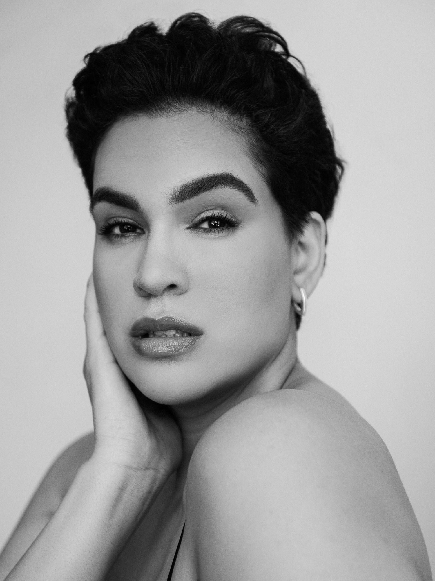 Dariana Casado - black and white portrait  looking over shoulder, hand slightly touching side of face