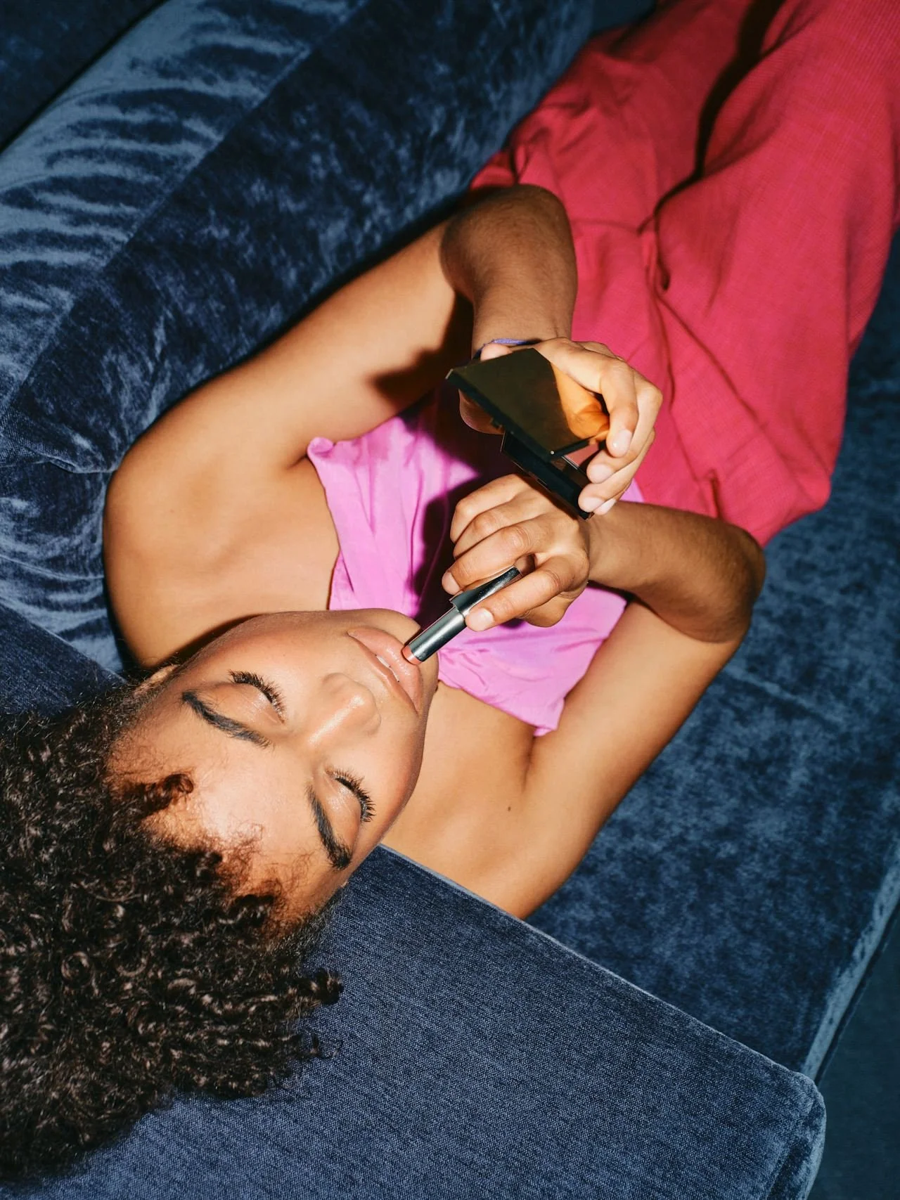 woman on couch applying makeup