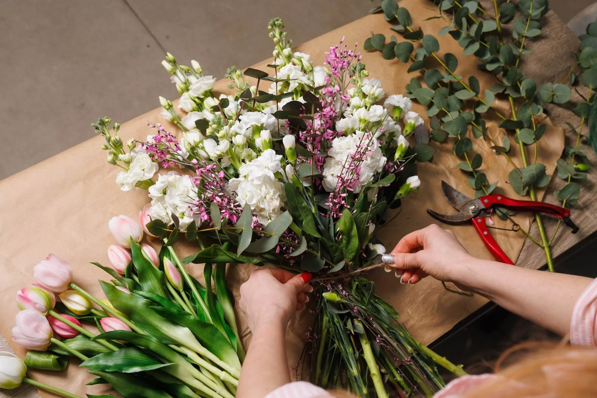 flatlay of woman hands tying flowers