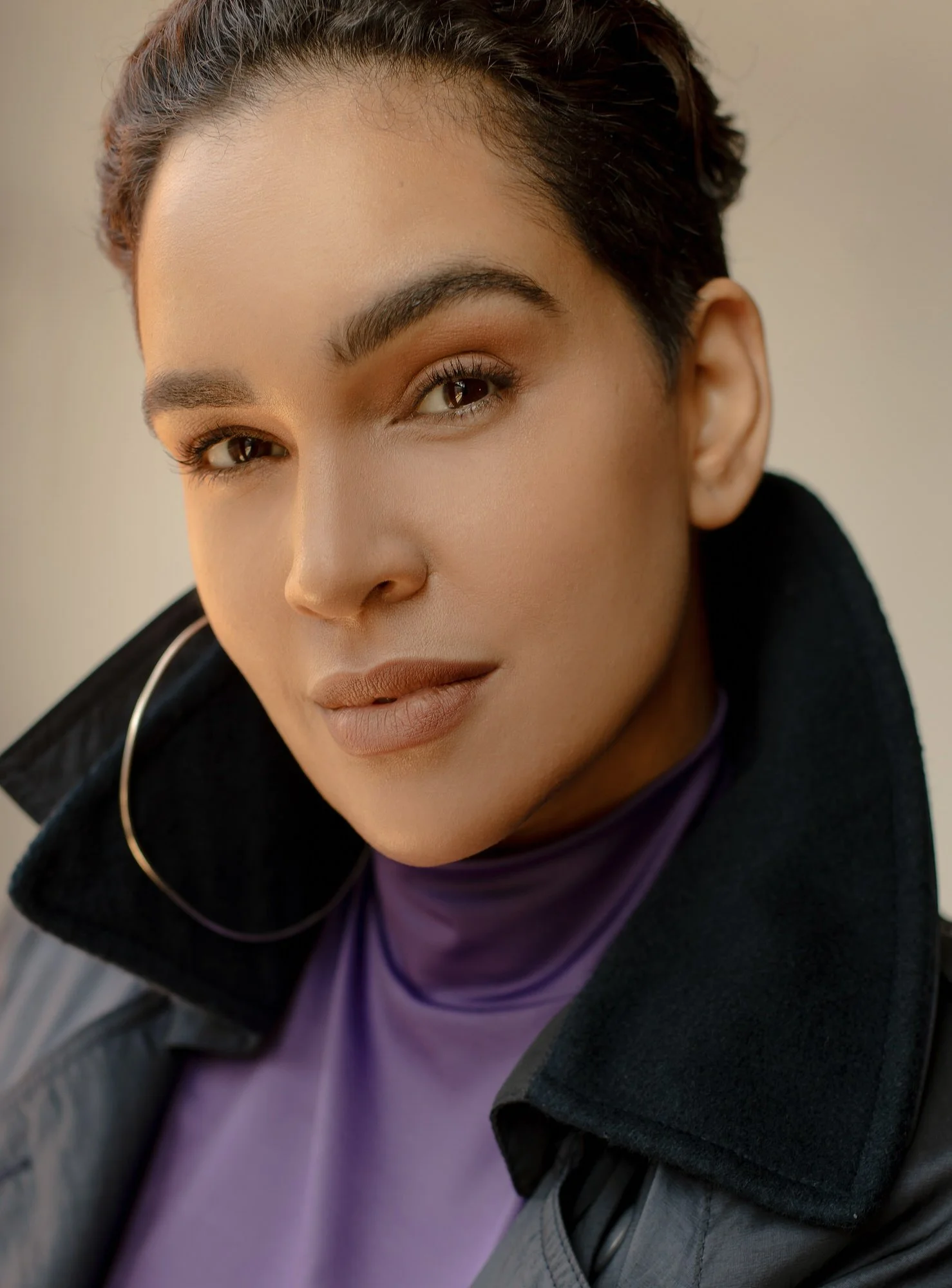 Dariana Casado in purple tee, black jacket and hoop earrings