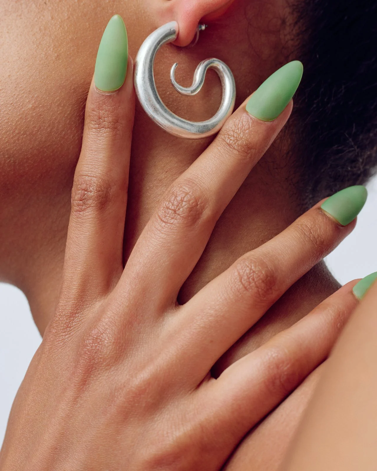 close up of woman's earring and hand green nail polish