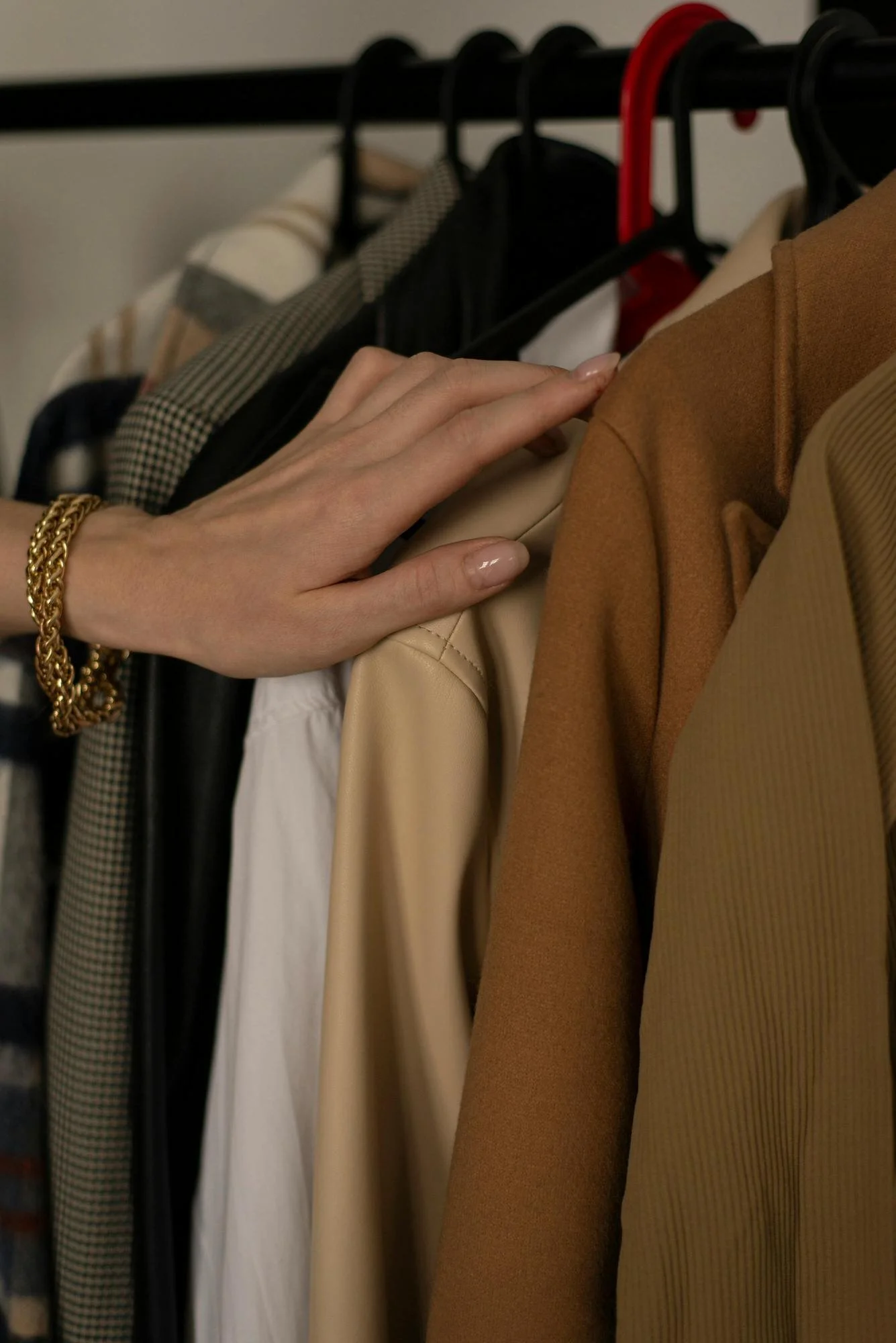woman's hand touching rack of clothes