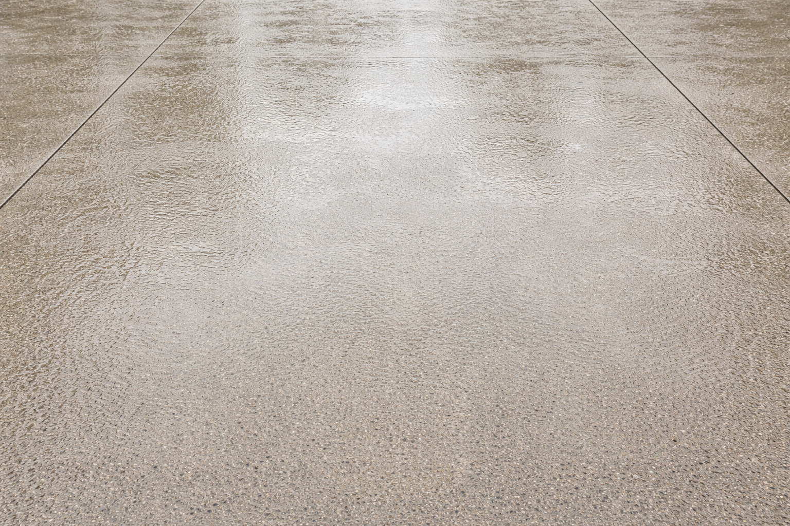 Close-up view of a beige, textured floor or pavement with visible grout lines.