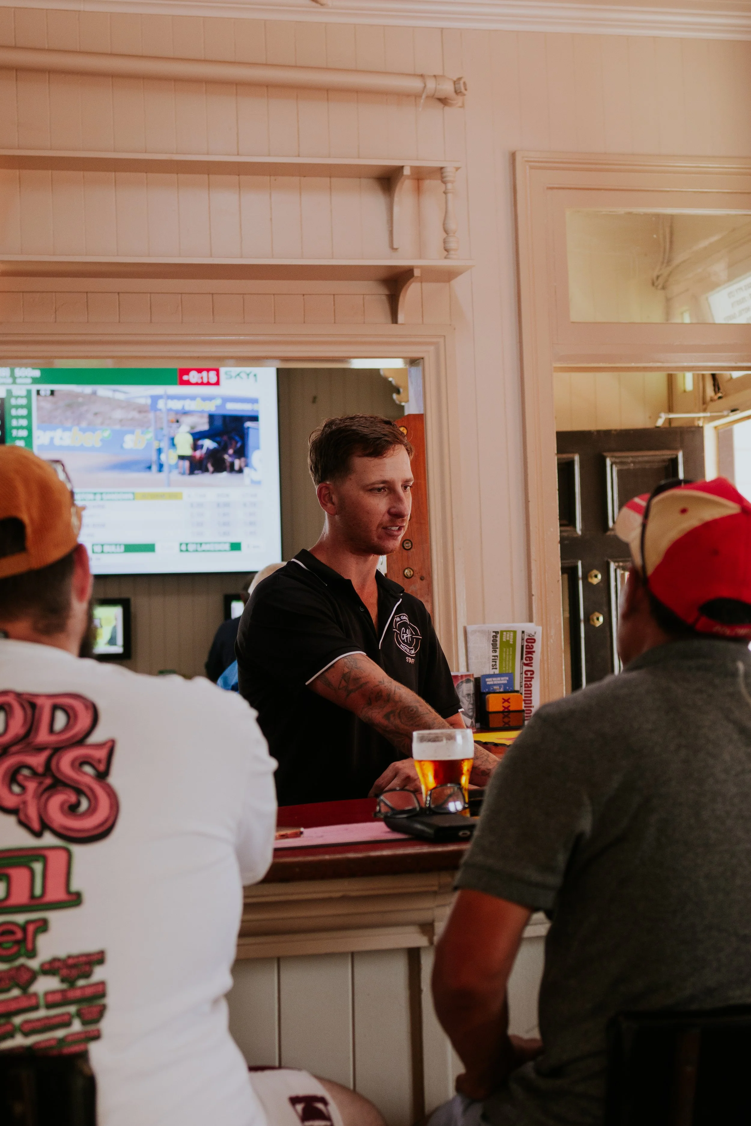 Bartender serving drinks to customers at a bar in a casual setting.