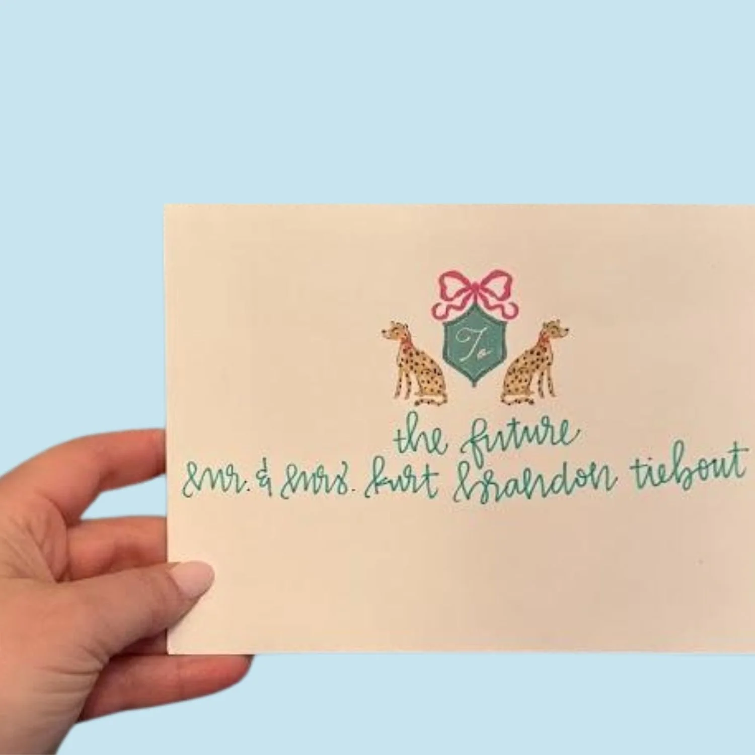 A custom card with a beige background, decorated with two giraffes and a pink bow at the top.