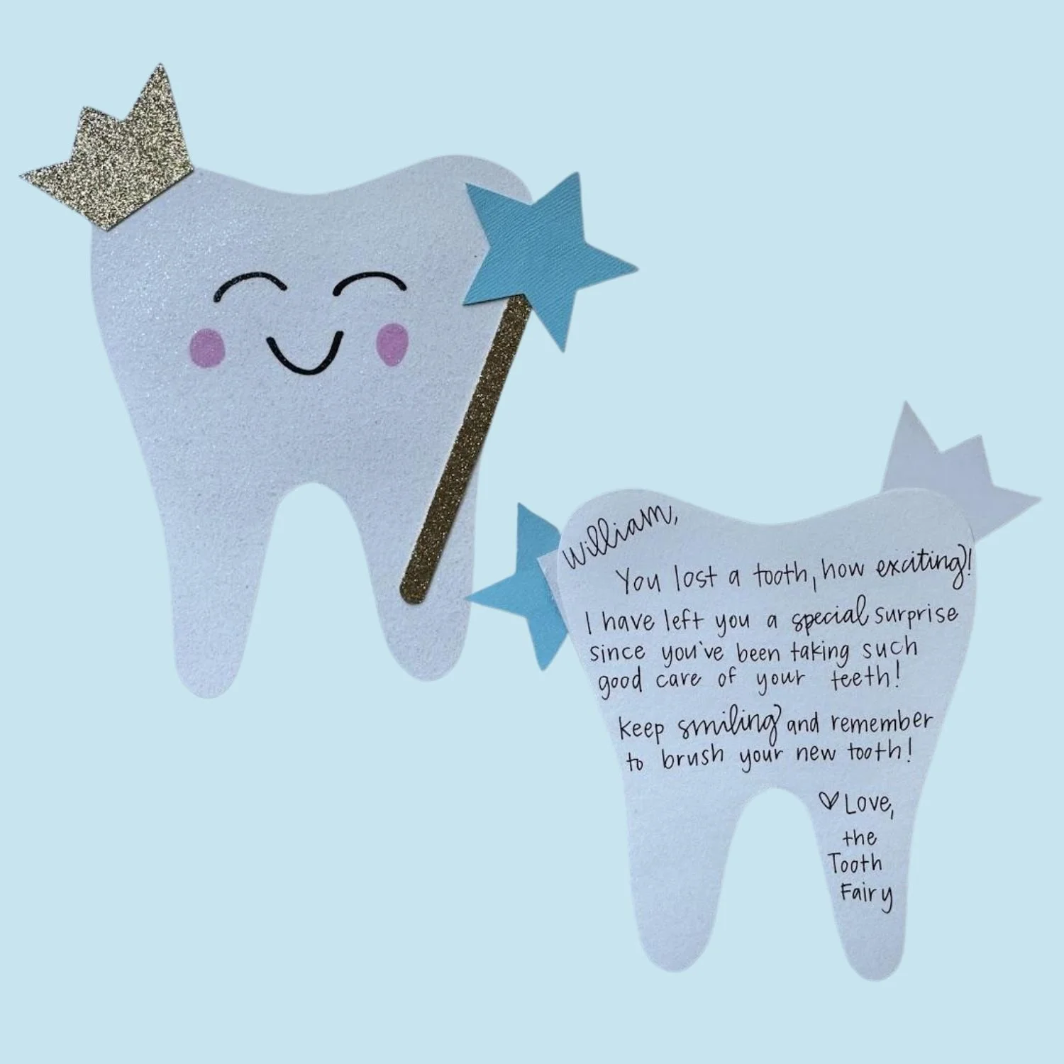 A cute paper cutout of a smiling tooth with pink cheeks, wearing a silver crown, holding a blue star wand. Next to it is a note shaped like a tooth with a handwritten message about a lost tooth and a reminder to brush the new tooth, signed by the Tooth Fairy.