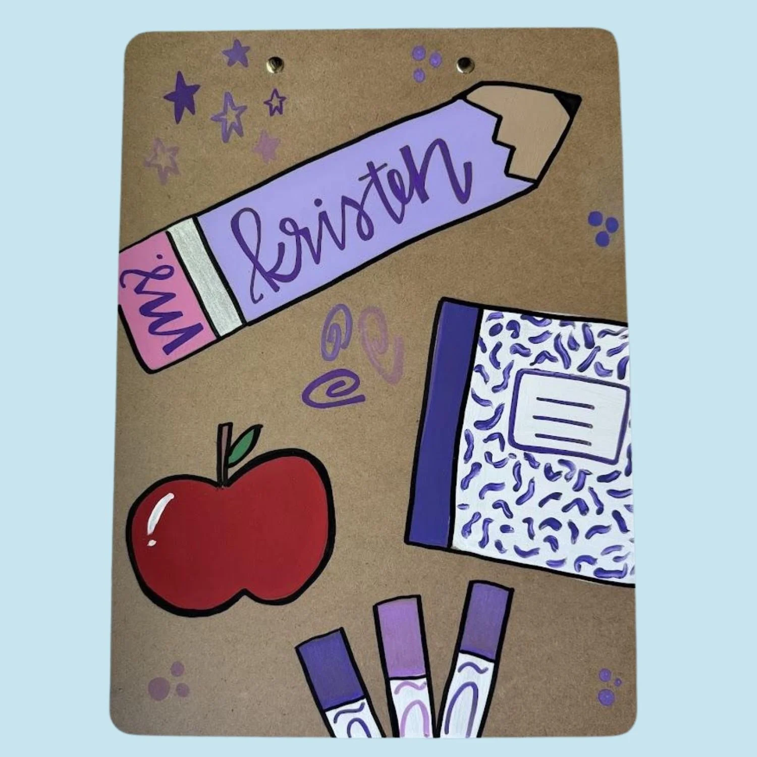 Drawing of school supplies on a brown paper surface, including a purple glue stick labeled 'my' and 'glue', a notebook with a blue and white pattern, a red apple, and three purple pens.