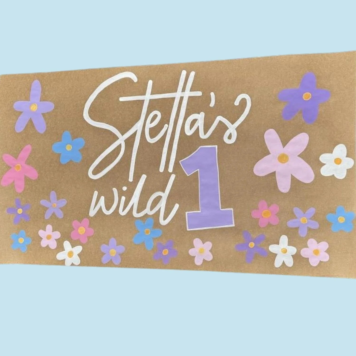 Colorful birthday banner for Stella with floral decorations, reading "Stella's wild 1" in a playful script and block letters.