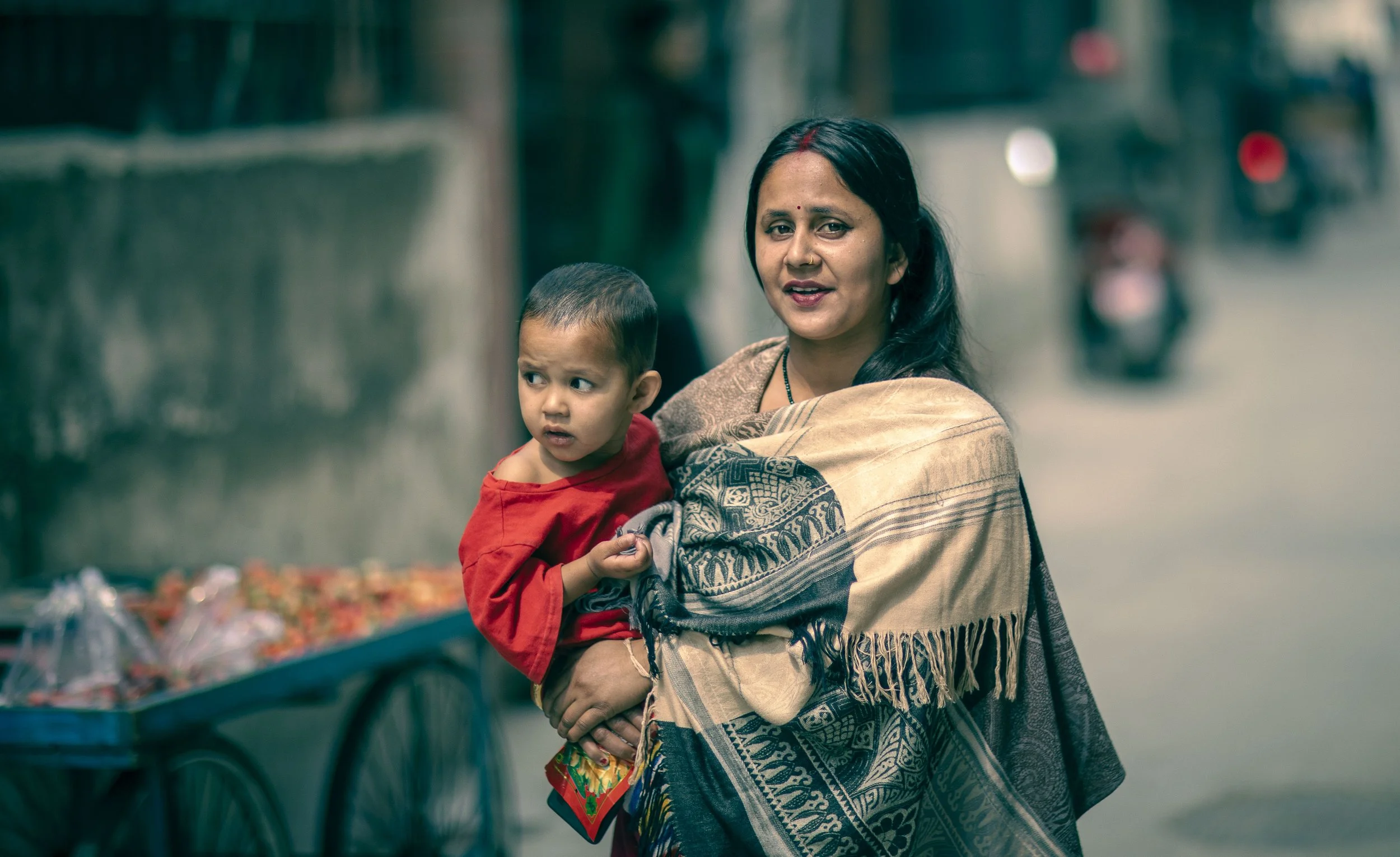 Young woman carrying child at Tilganga Eye institute Kathmandu street photograph Simon Shattky
