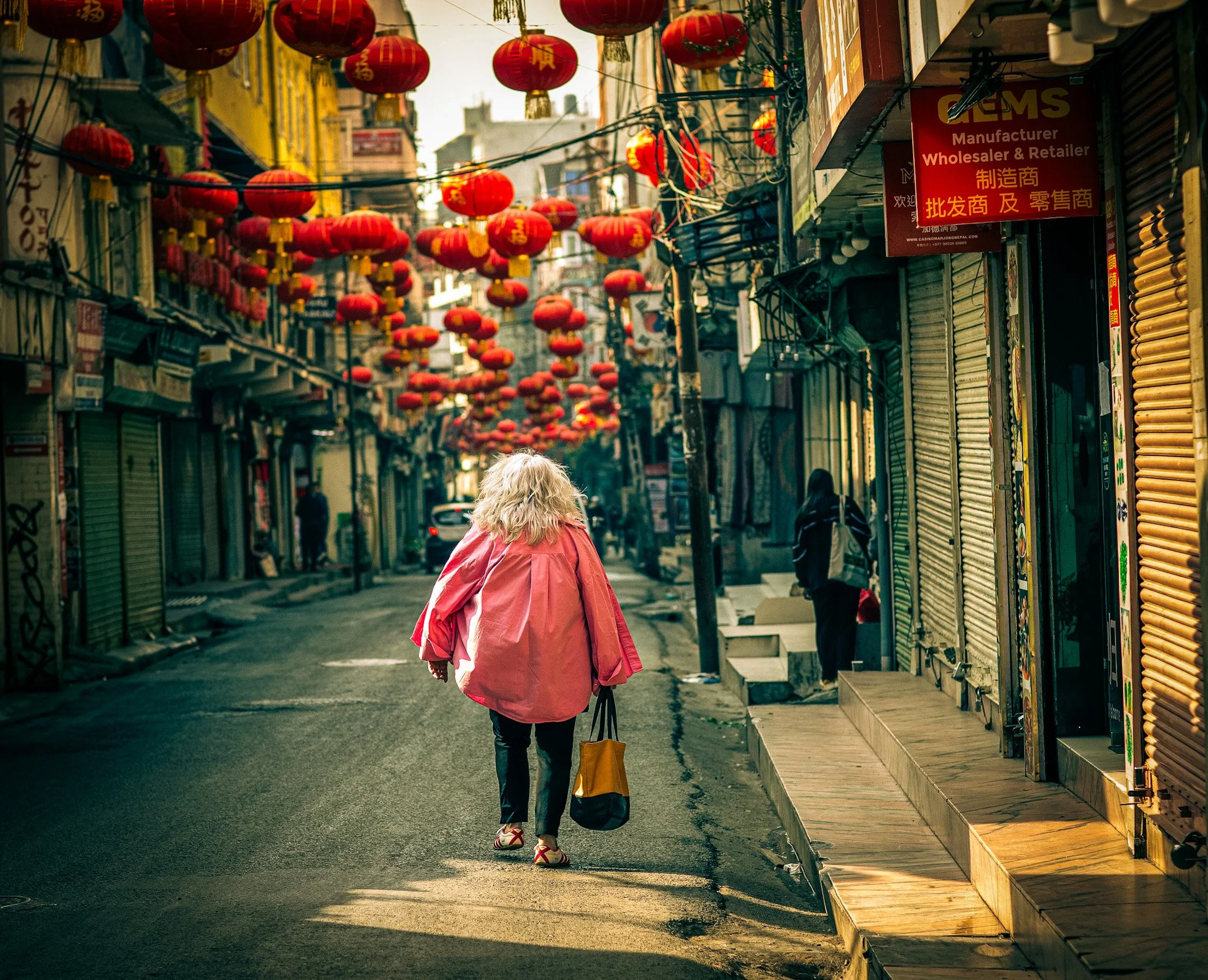 Street photography Angela Griffen in Thamel Kathmandu. Red chines lanterns overhead by photographer Simon Shattky
