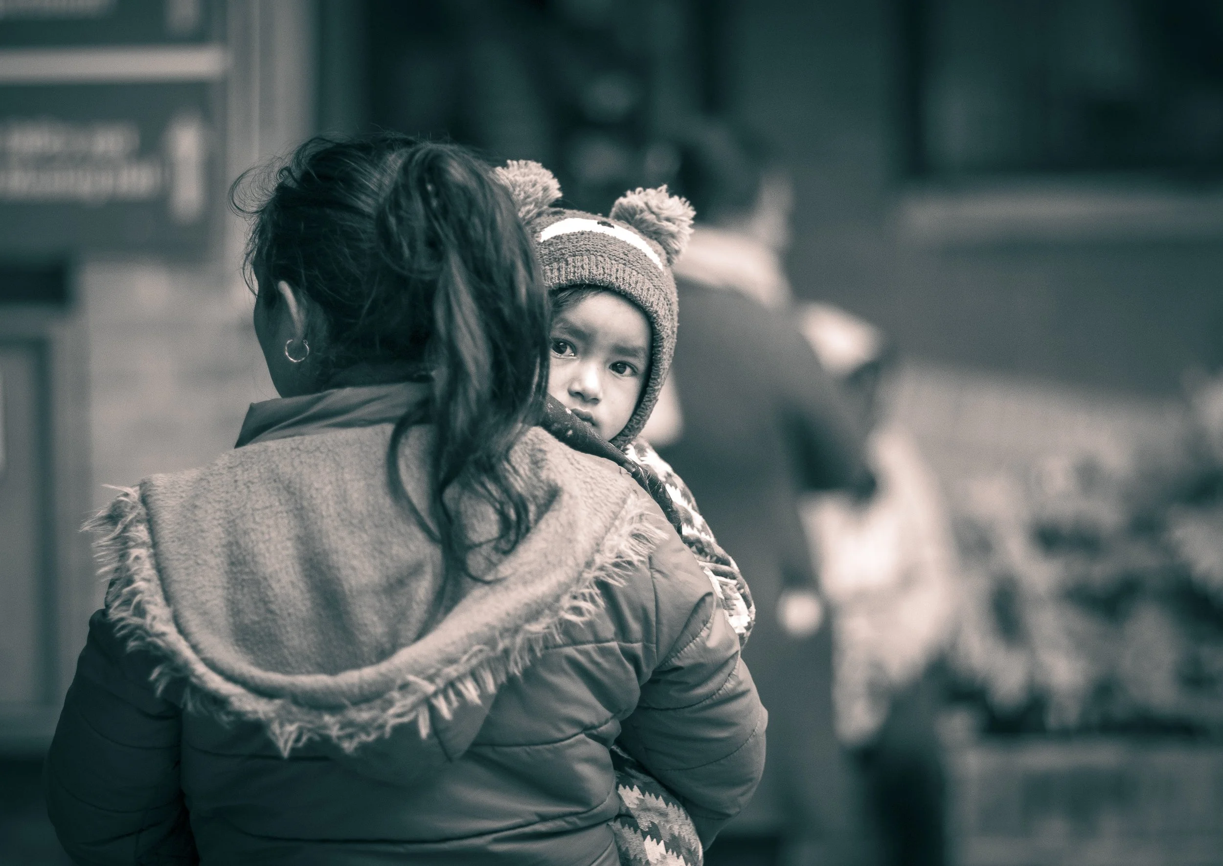 Mother and young child with knitted hat waiting candid black and white portrait Tilganga Eye Institute Kathmandu Nepal Simon Shattky

