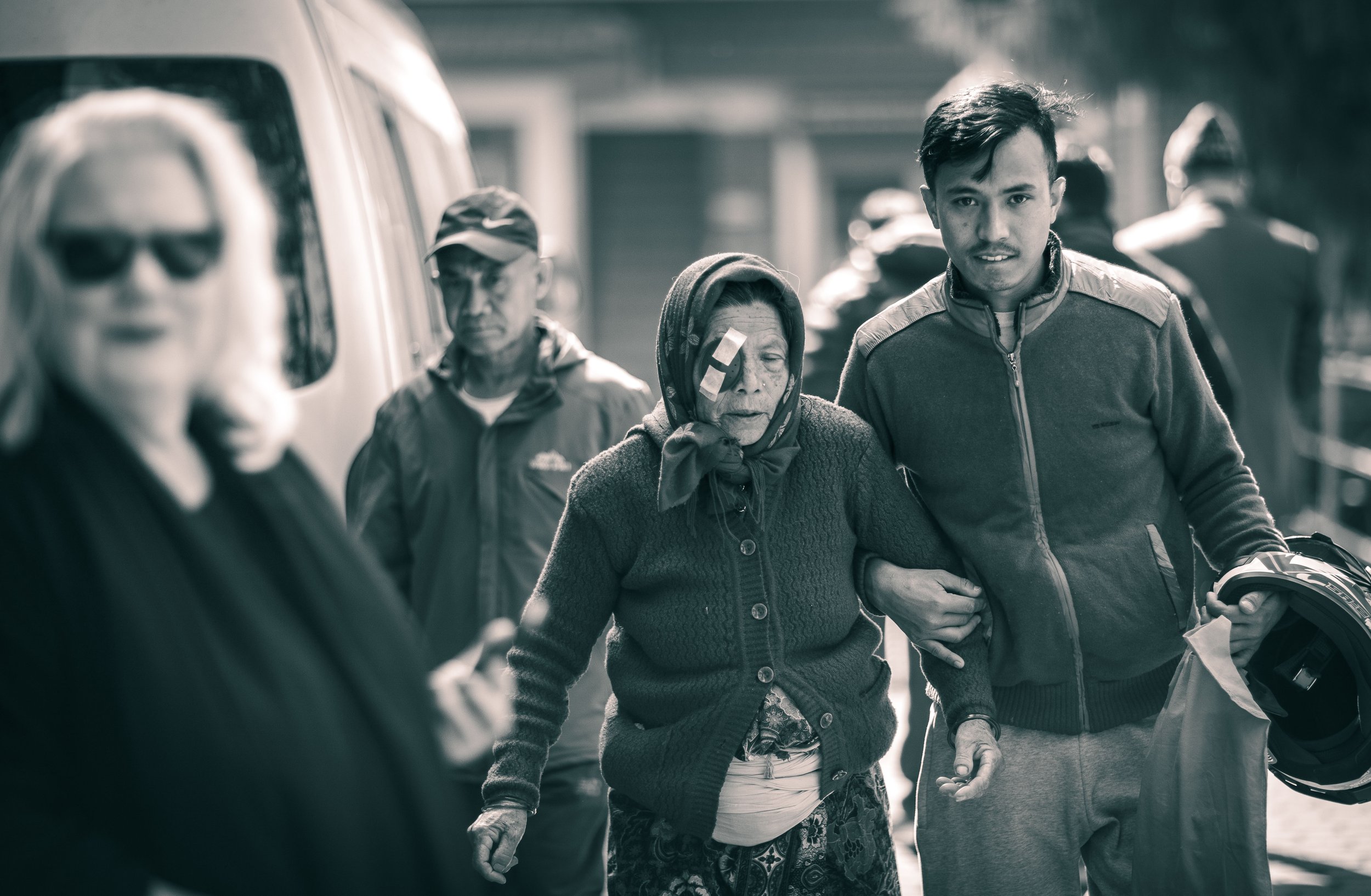 Candid black and white photograph Post surgery cataract patient leaving hospital supported by family Tilganga Eye Institute Kathmandu Nepal Simon Shattky
