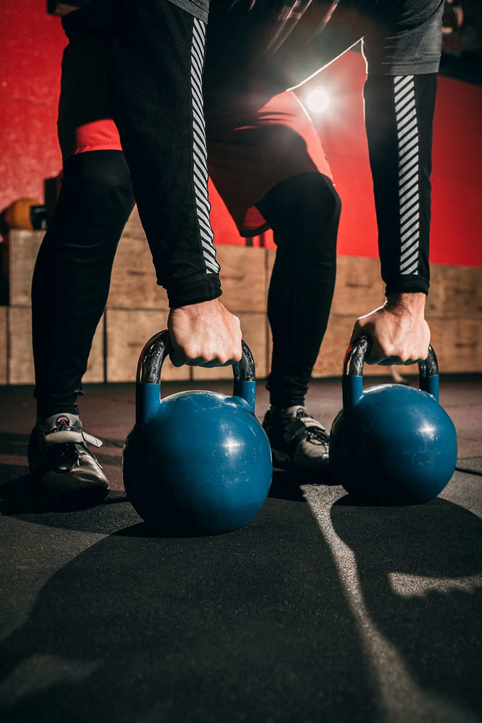 two hands lifting two blue kettlebells