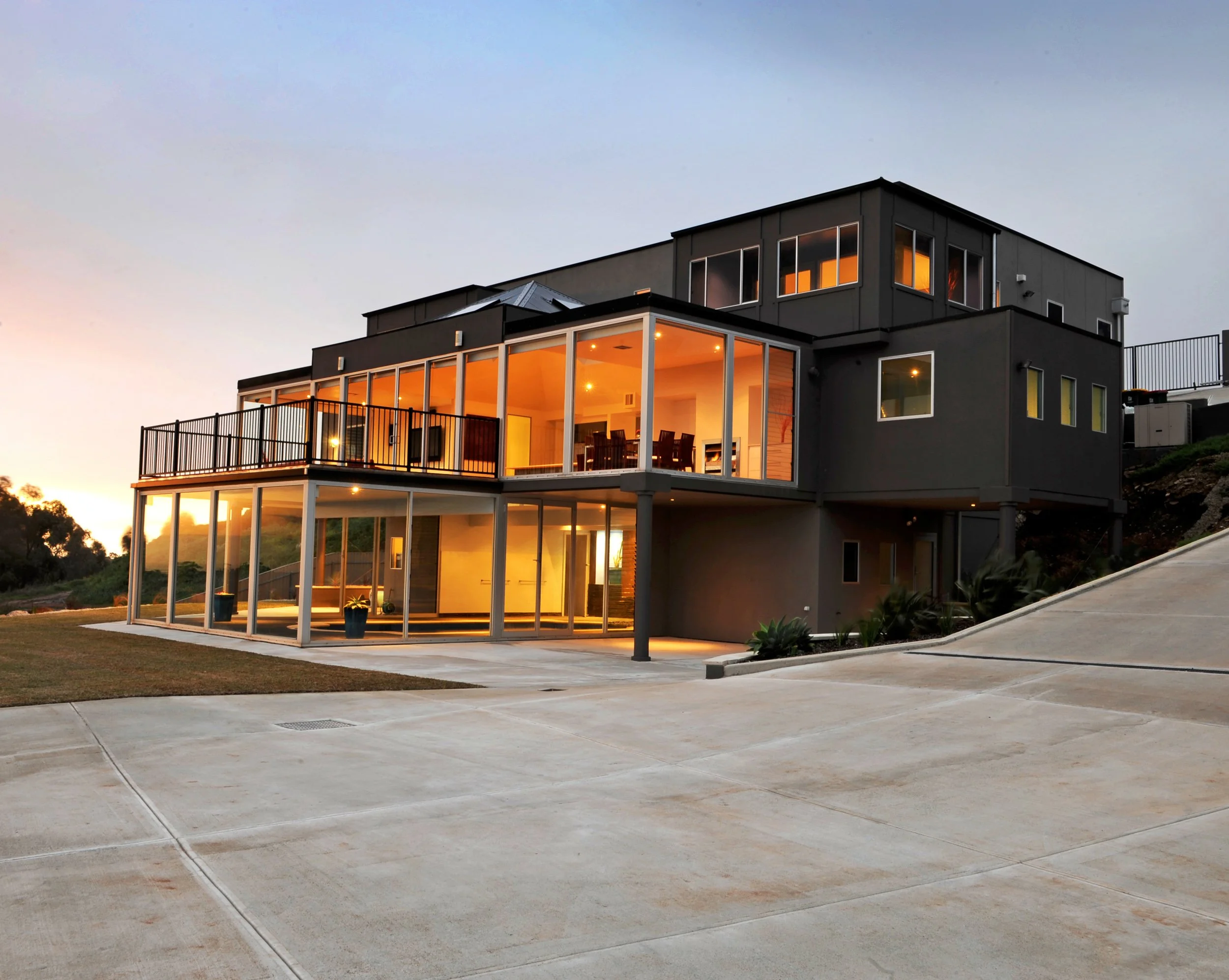 Modern multi-level house with large glass windows and balconies at dusk