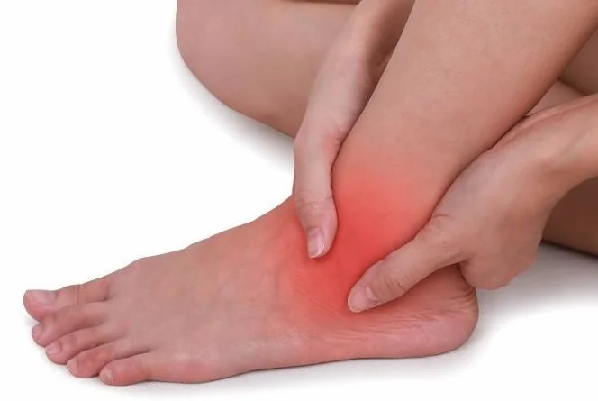 Person holding ankle with redness and pain indication.