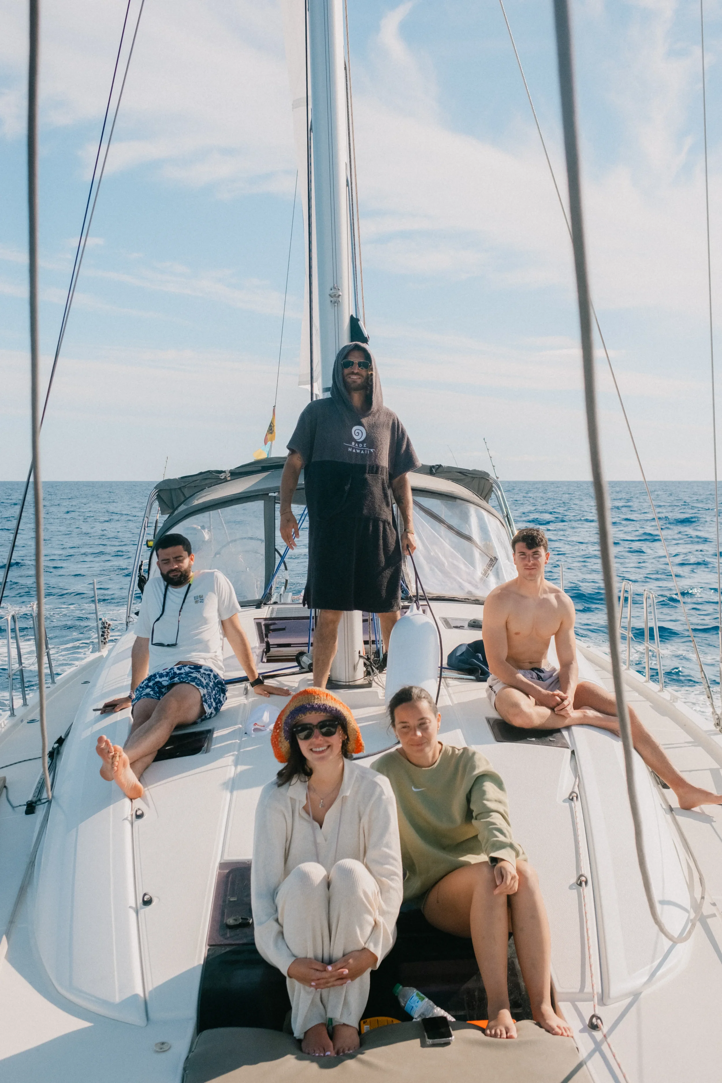 A group of people on a boat enjoying a sunny day, with clear blue skies and the ocean in the background.
