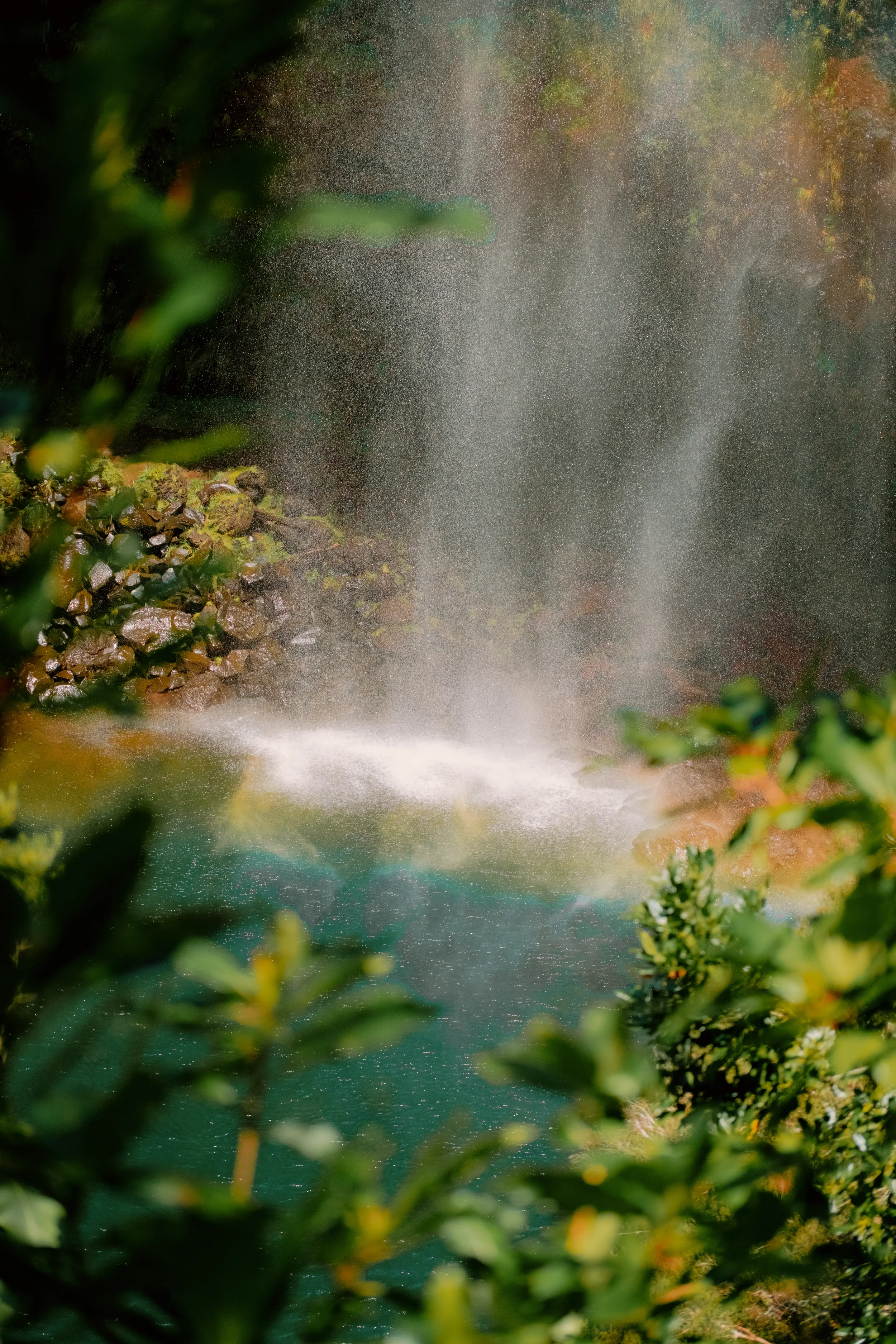 A waterfall flowing down a rocky cliff surrounded by greenery.