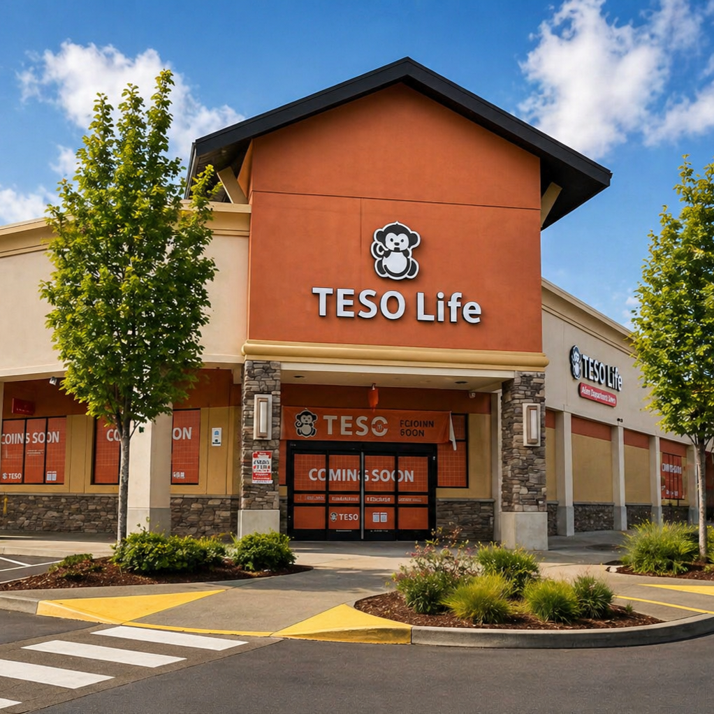 A new TESO Life store under construction, with orange and beige exterior walls, a logo featuring a cute bear, and yellow ticketing at the entrance, with a parking lot and trees in the foreground and a partly cloudy sky in the background.