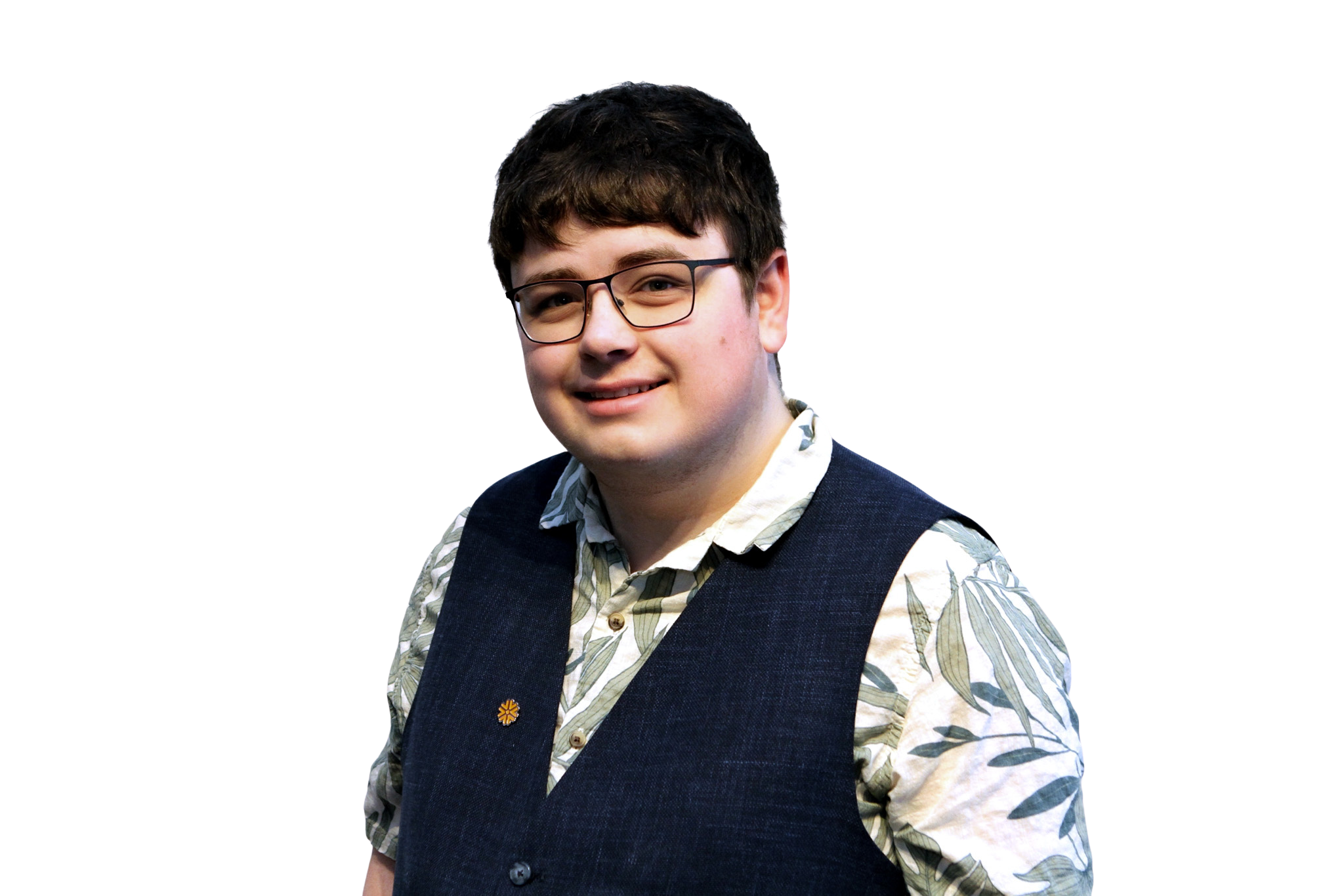 Portrait of a young man with short dark hair, wearing glasses, a floral button-up shirt, and a dark vest, smiling at the camera.