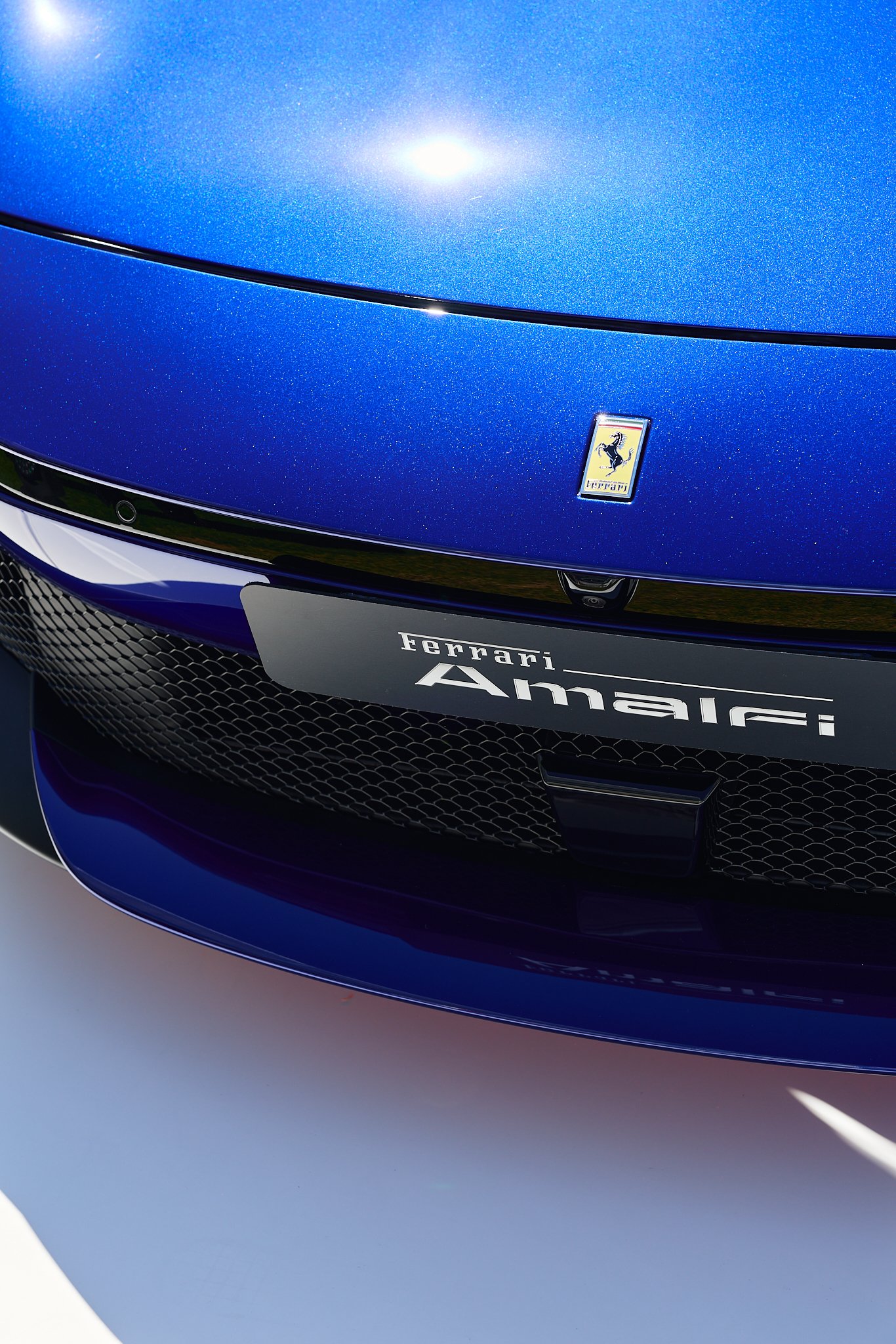 Close-up of the front of a blue Ferrari car, displaying the Ferrari logo and the 
