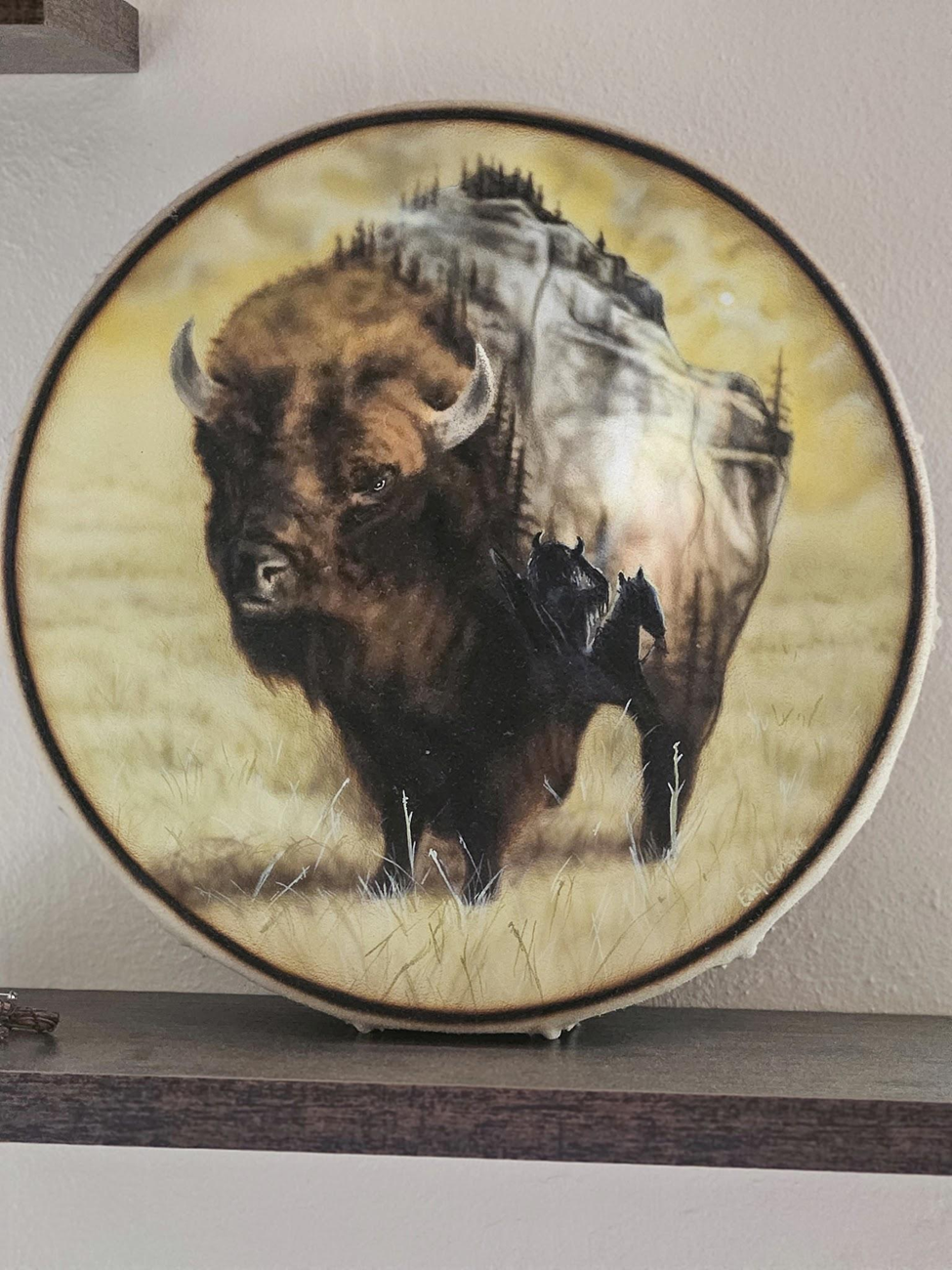 Custom airbrush buffalo artwork on circular surface with landscape and wildlife scene in warm tones