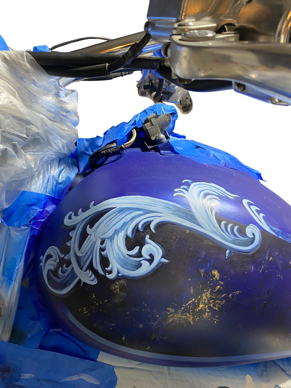 Custom airbrush motorcycle tank with hand-painted ornamental scrollwork and metallic blue finish