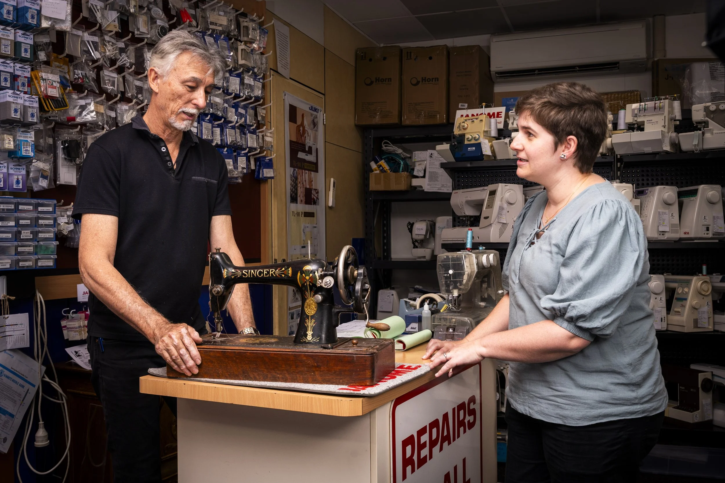 A lady getting a quote from the owner regarding the repair of her vintage sewing machine.