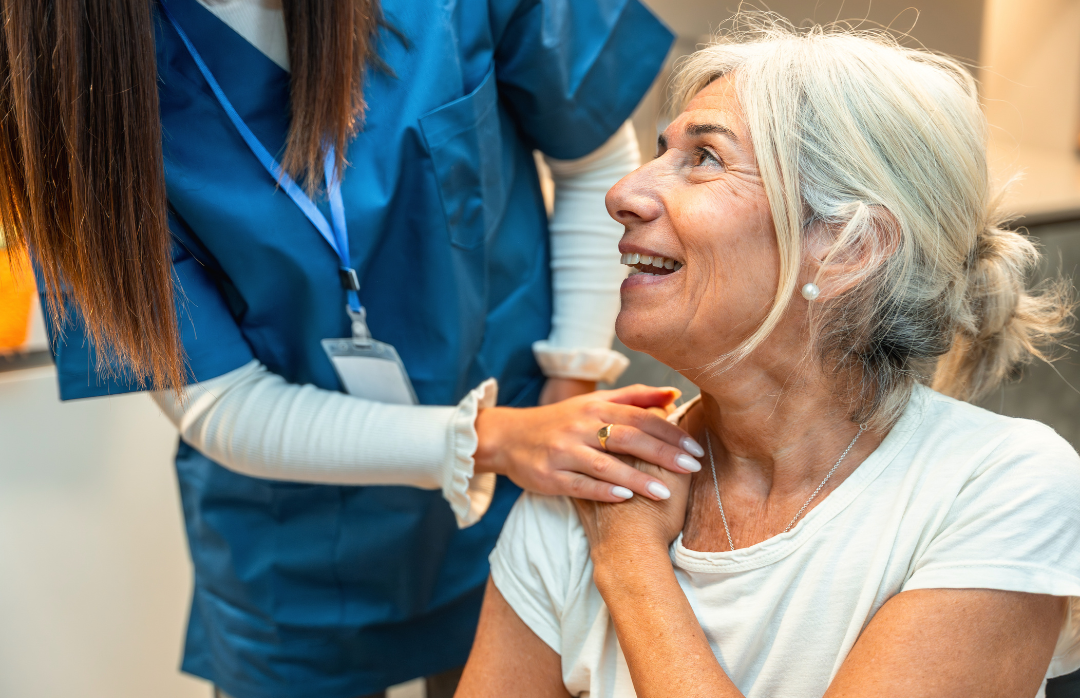 An elderly woman receiving a vaccination from a healthcare professional in a clinical setting.
