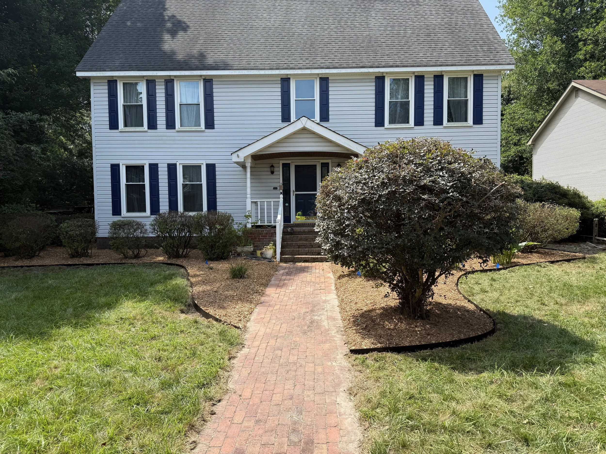 Shrubs cut back extensively, steel landscaping border installed, cedar mulch installed.