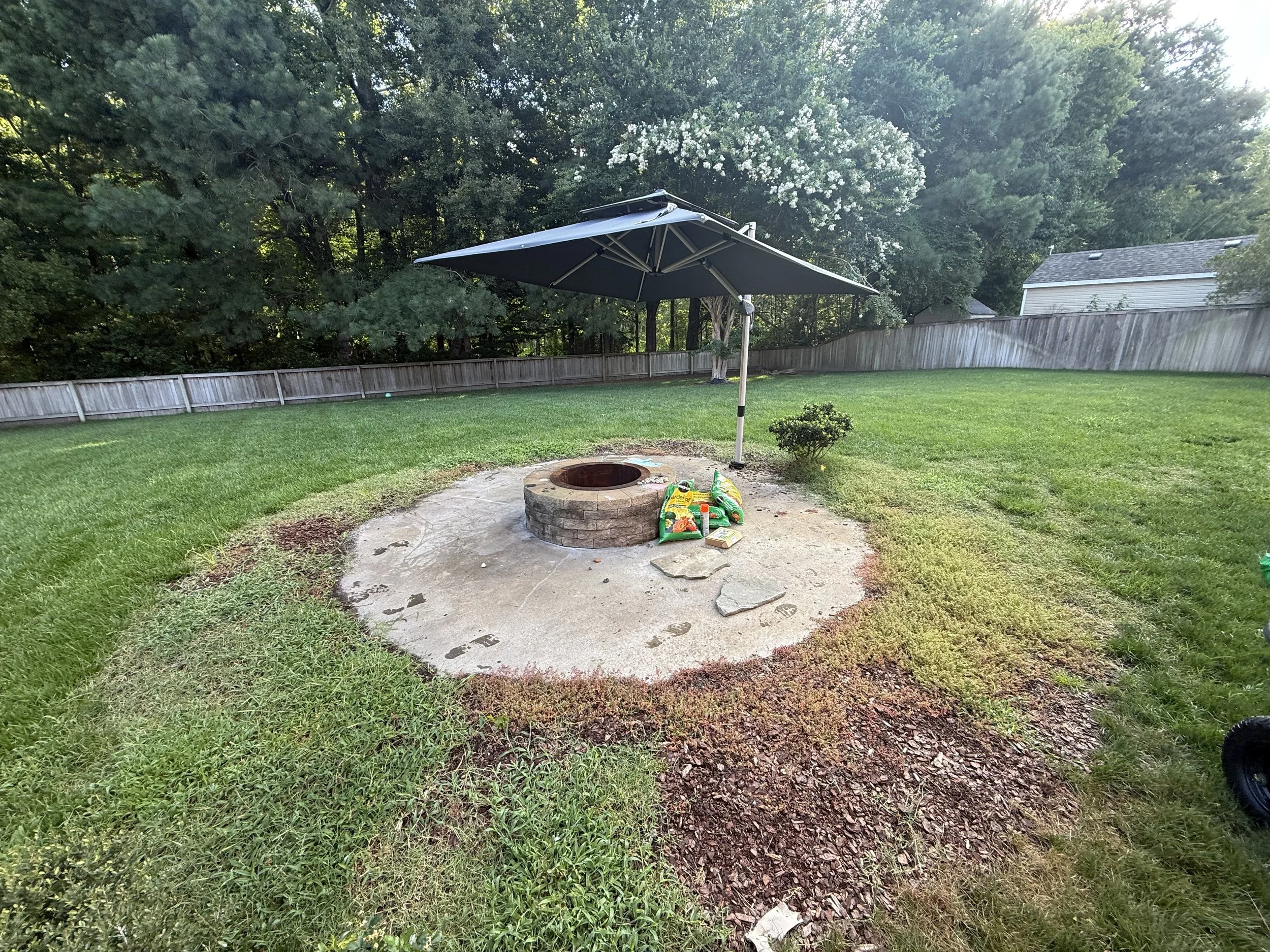 Heavy weed infiltration into what was once a mulch bed surrounding this fireplace area. 