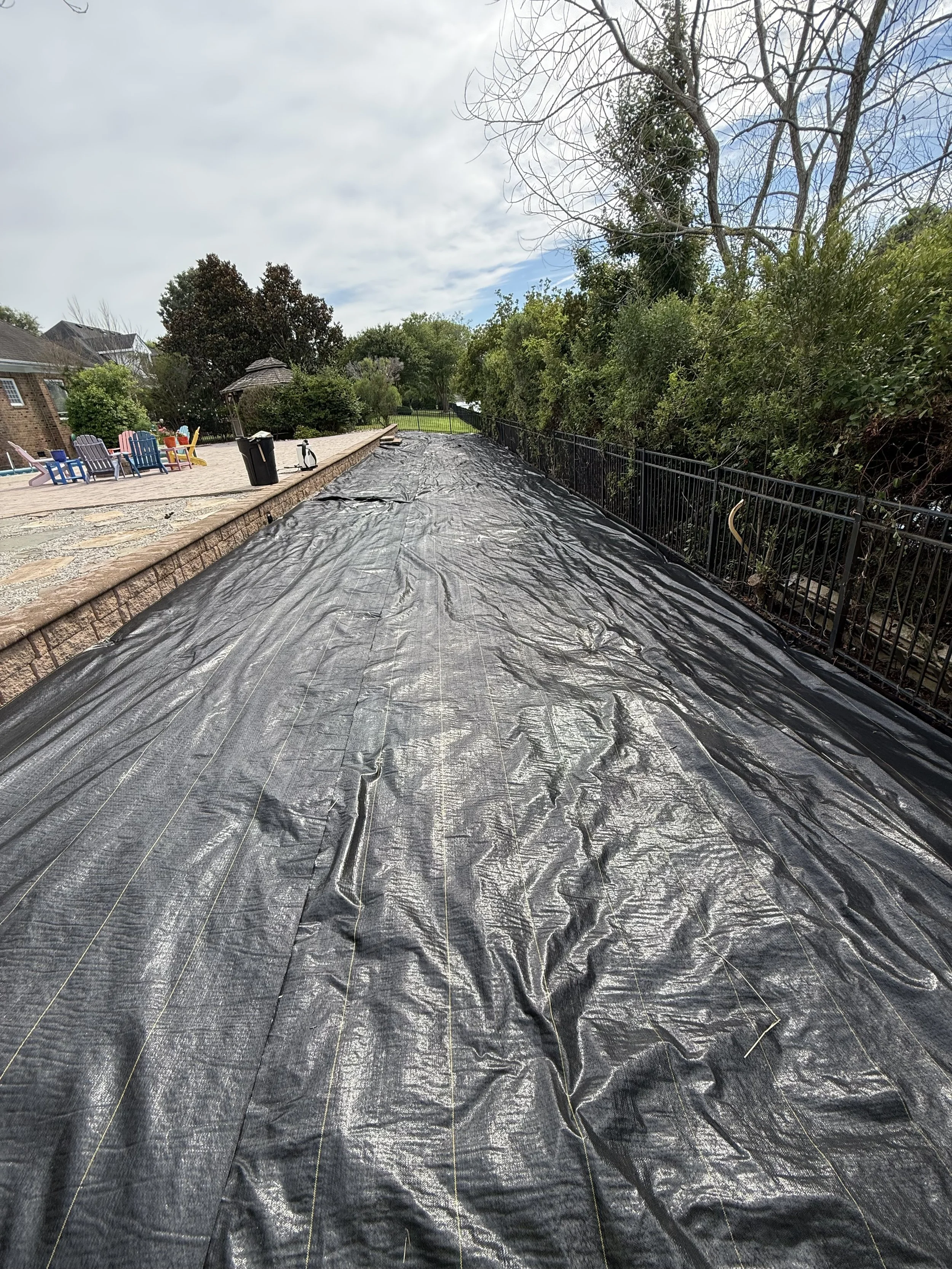 Rock Install IMG 3. Once the debris was removed, we installed landscape fabric over the entire 1,800 sq ft area and steel edging at the bottom of the slope to prevent rocks from sliding. 
