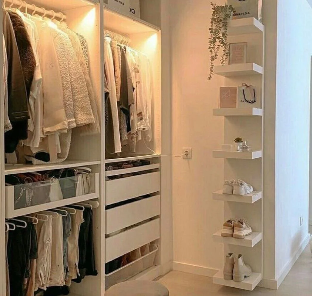 Organized closet with hanging clothes, shoes, and decorative shelves