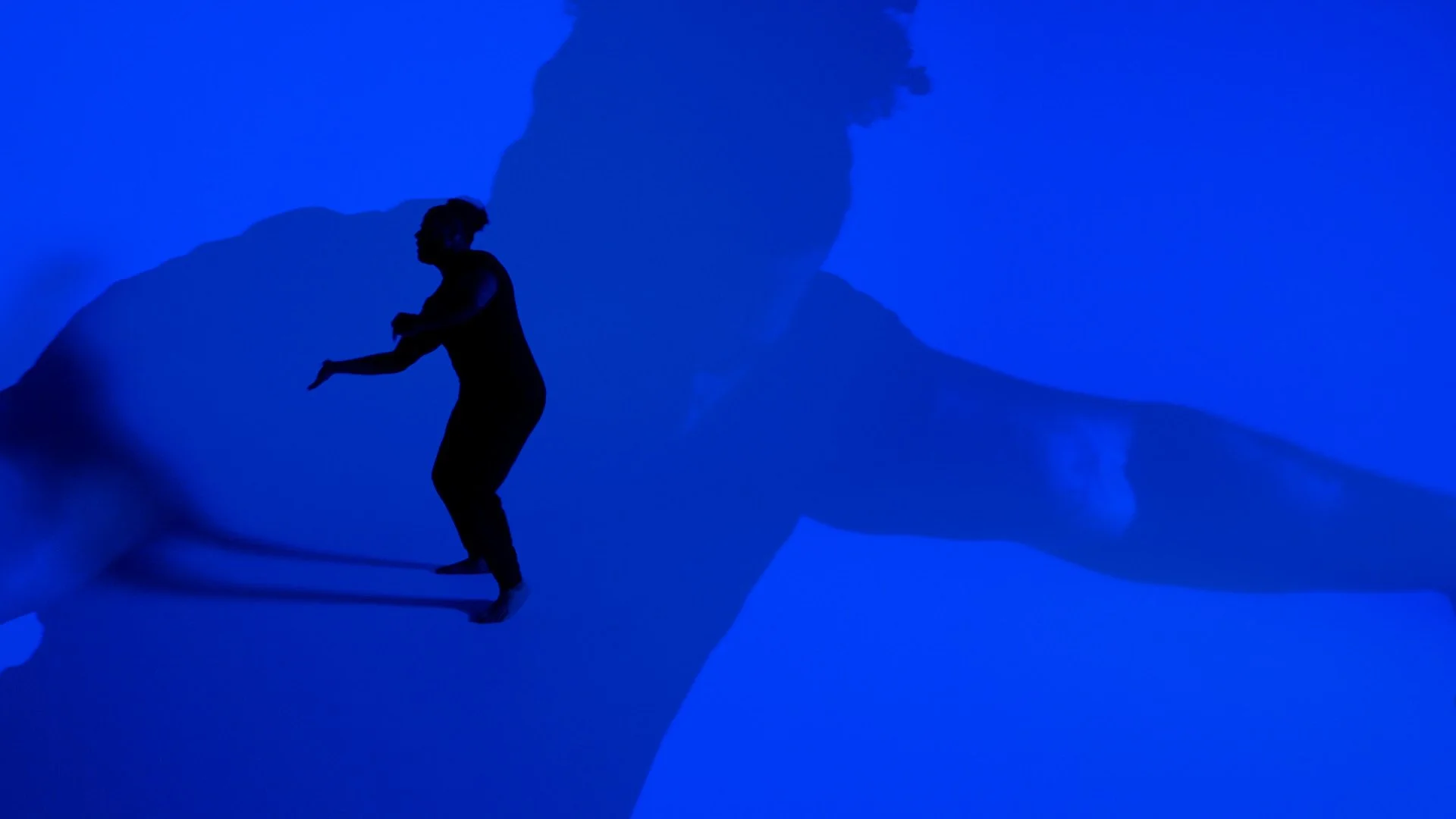 A silhouette of a person appears to balance on the edge of a ledge with a blue background, creating a double exposure effect of the person's profile.