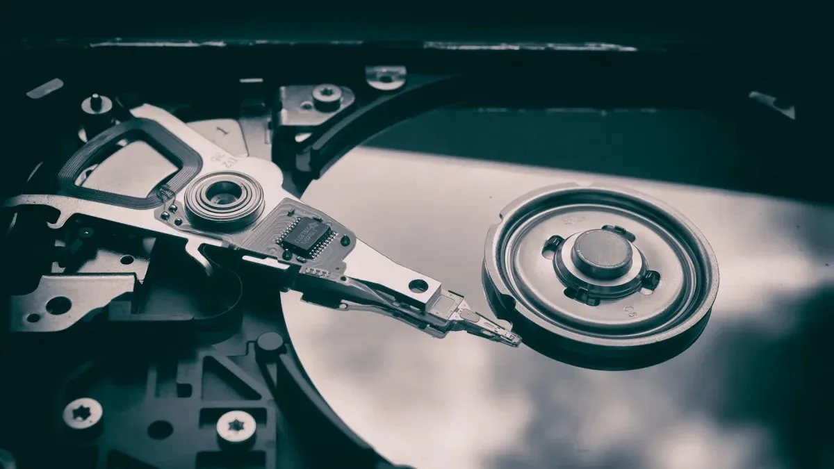 Close-up of an opened hard disk drive showing the spinning platter and read/write head assembly.