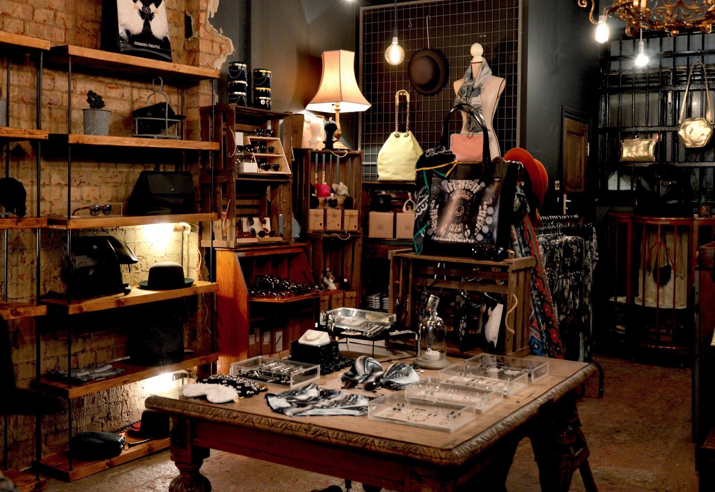 Interiores de una tienda de accesorios de moda con varias estanterías y mesas que muestran bolsos, gafas, sombreros y joyería.