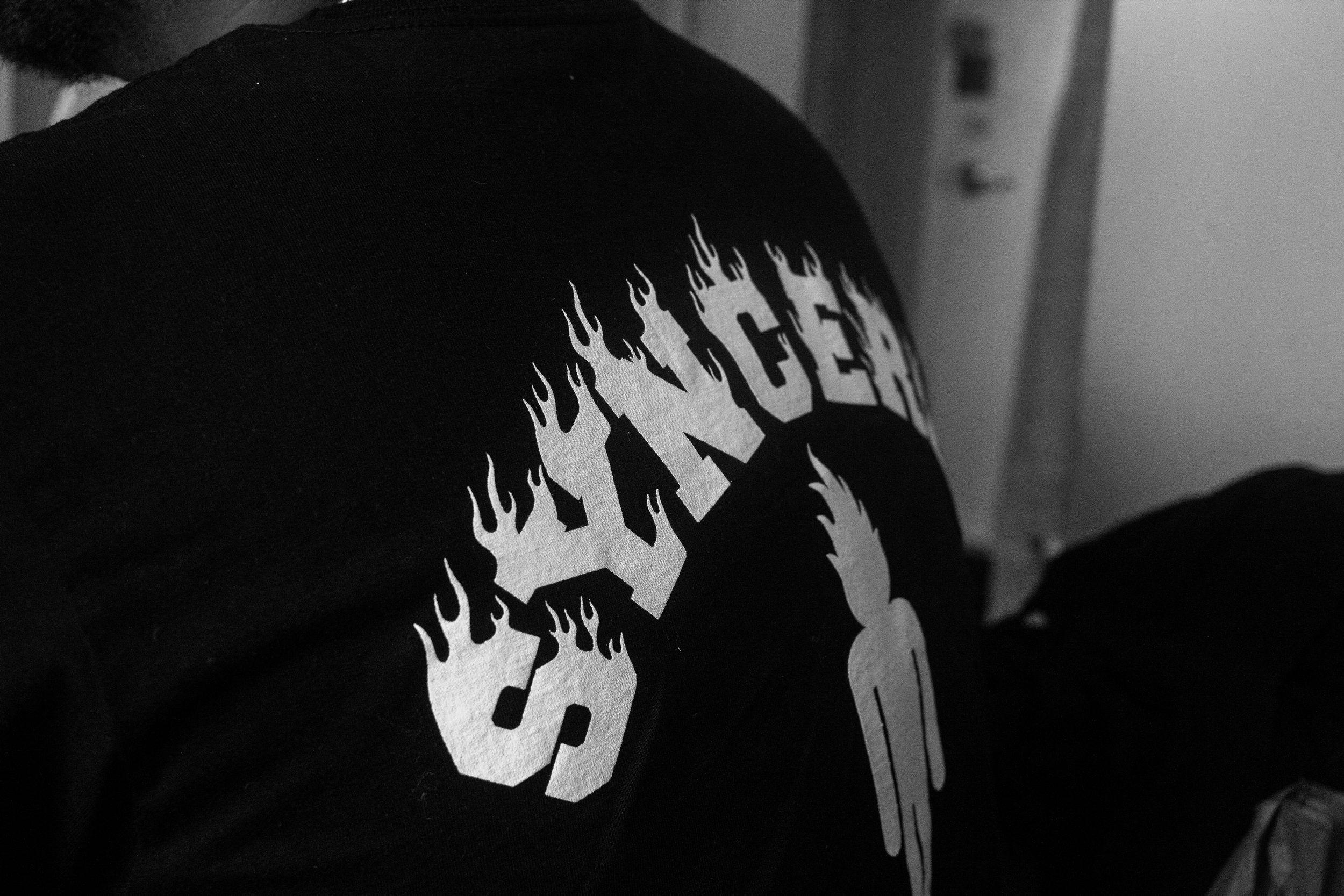 Close-up of a person wearing a black T-shirt with a white graphic design featuring stylized text and flames.