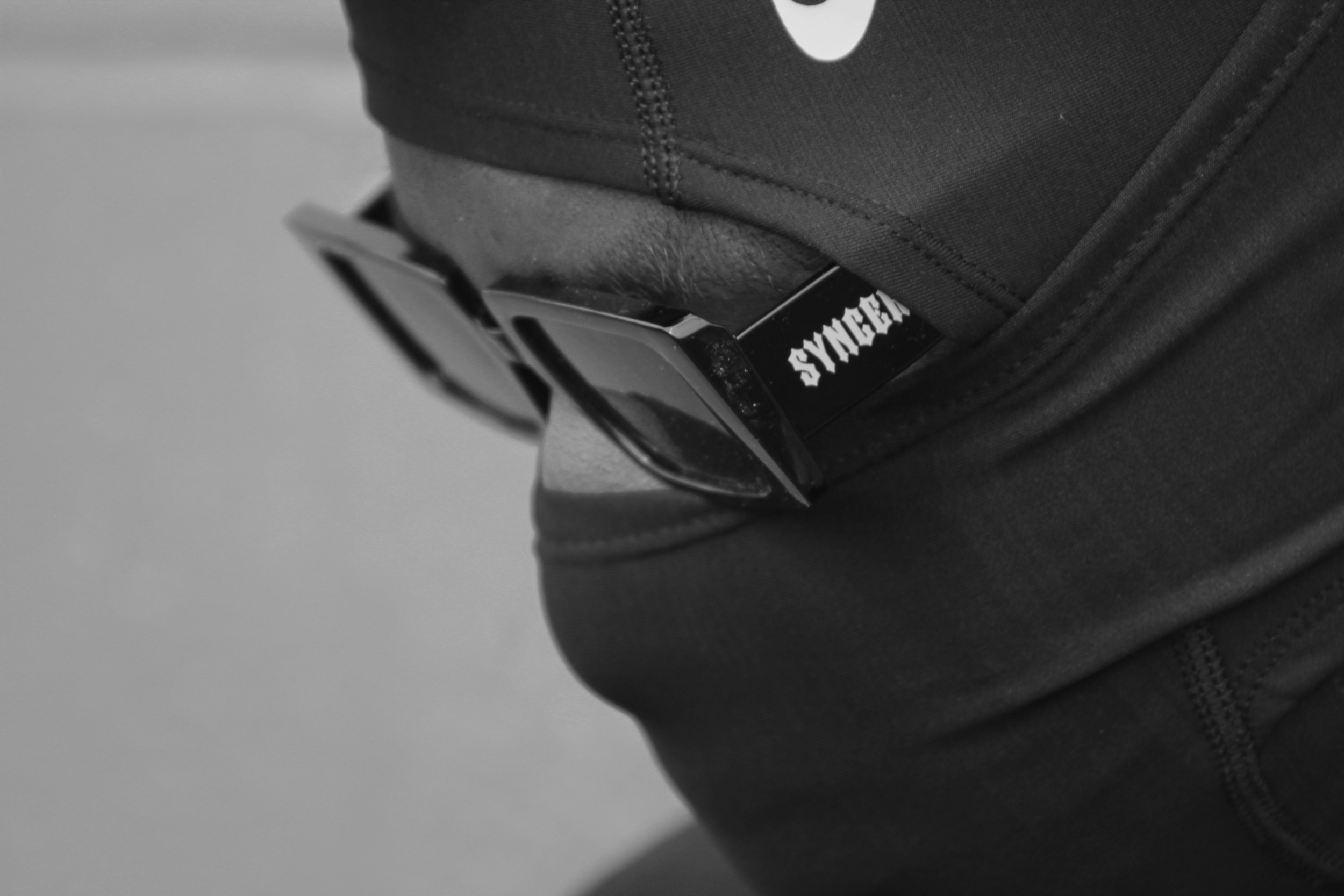 Close-up of a person's waist wearing black clothing with a visible waistband, and a Motorola device sticking out from the waistband with the word 'SYNG' visible on its side.