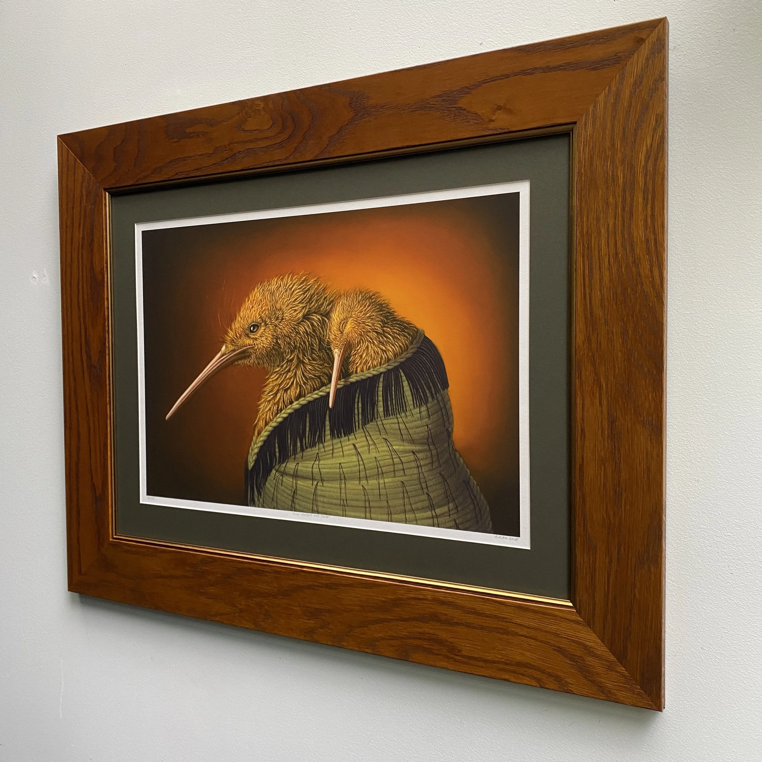 A beige speckled ceramic vase with a narrow neck holding dried plant stems, placed on a wooden surface with soft directional lighting and shadow.