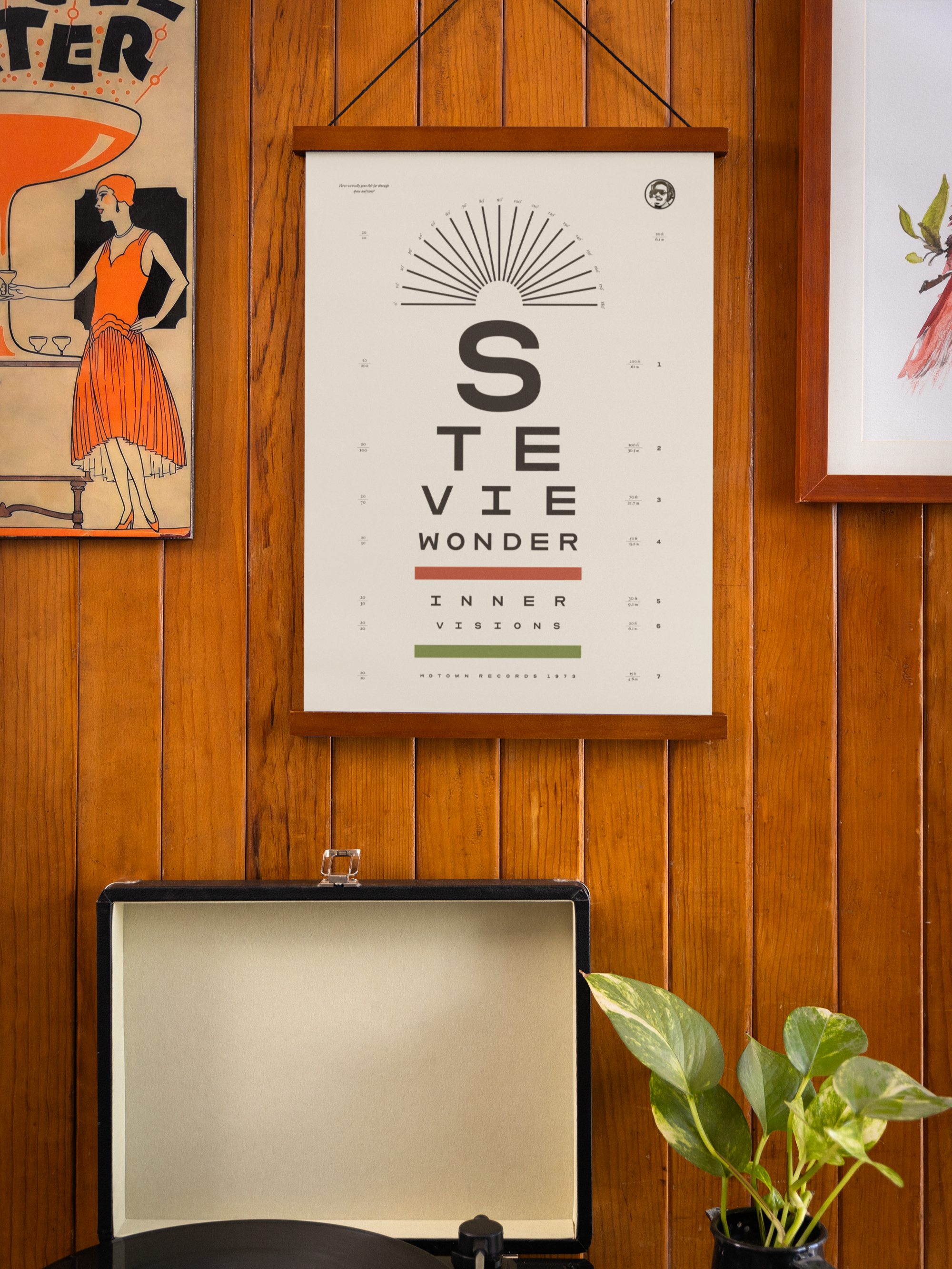 A wooden wall with a framed Stevie Wonder Innervisions eye chart poster, hanging above a turntable. 