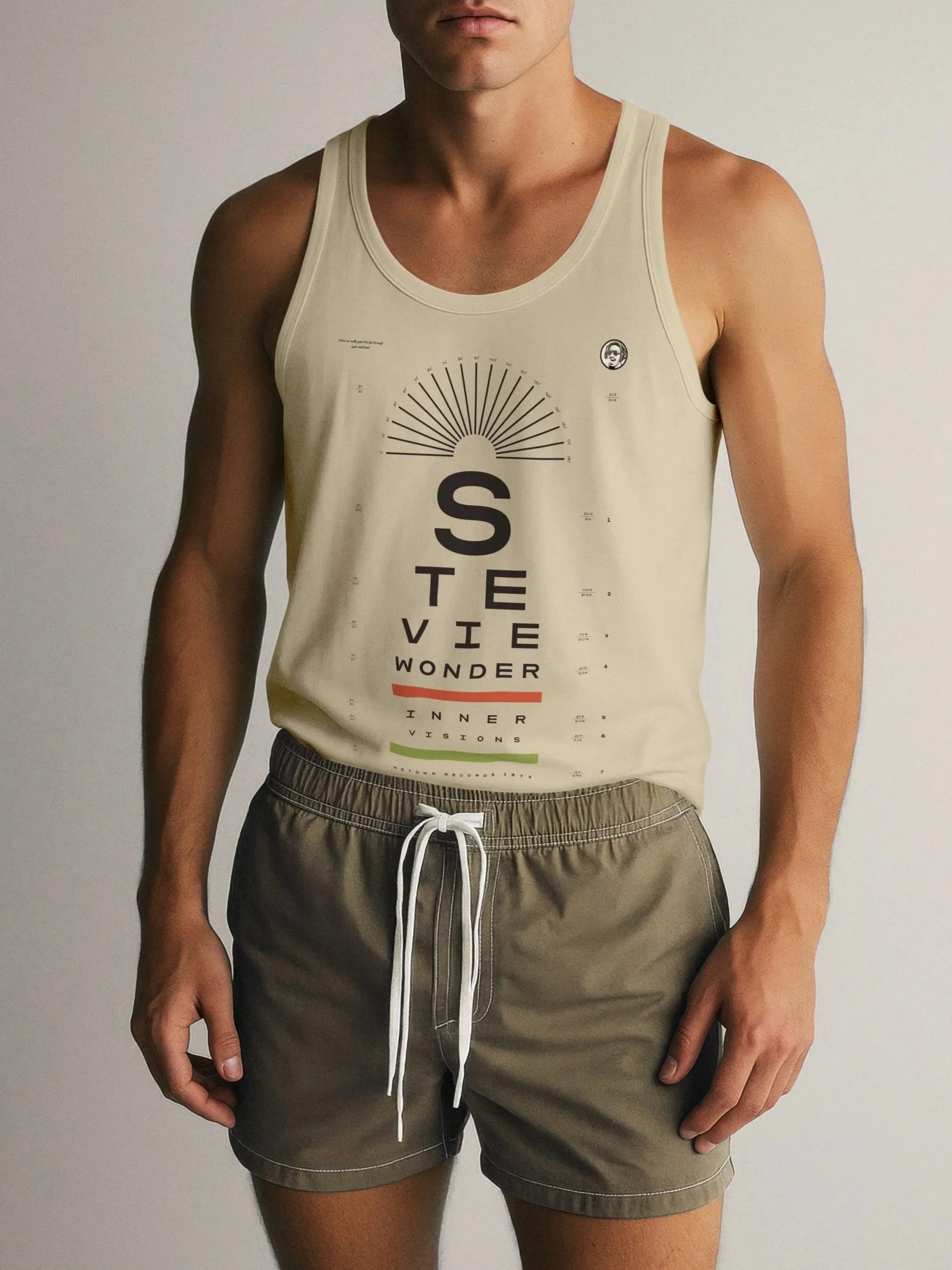 A studly fella wearing a beige sleeveless tank top with a Stevie Wonder Innervisions eye chart design, and olive green drawstring shorts.