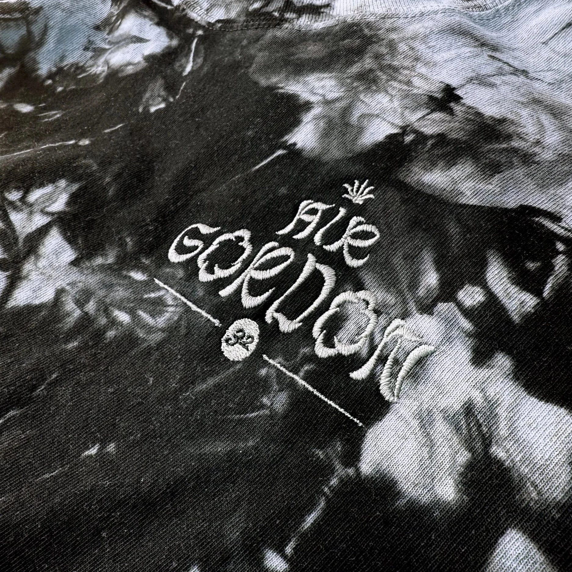 Close-up of black fabric with white embroidered text and design, reading "Air Gordon", with the number 32 below, and a small ornamental marijuana leaf above.