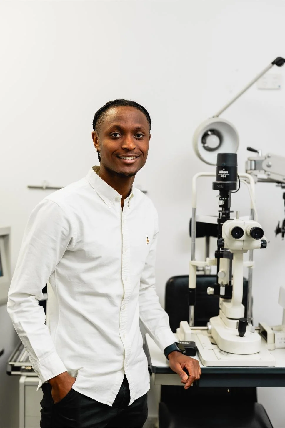Friendly optometrist standing in clinic beside eye testing equipment