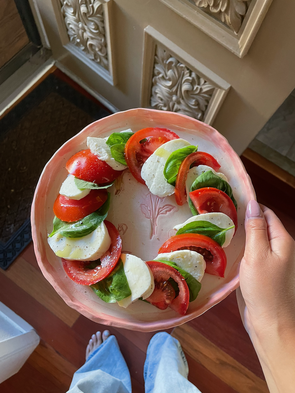 A plate of sliced tomatoes, mozzarella cheese, and fresh basil leaves.