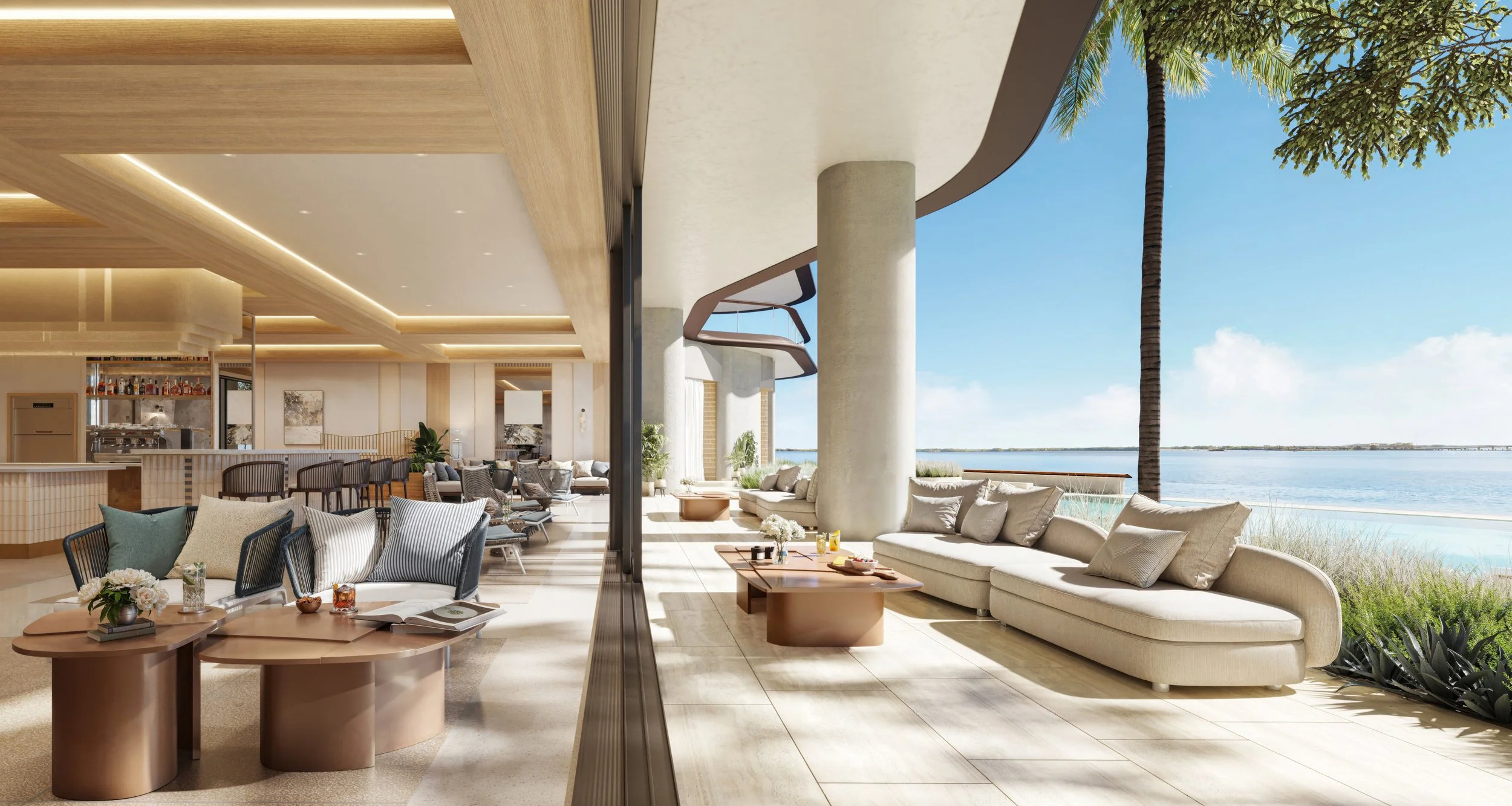 Luxurious indoor lounge area opening to an outdoor patio with ocean view, featuring beige sofas, wooden tables, and tropical plants.