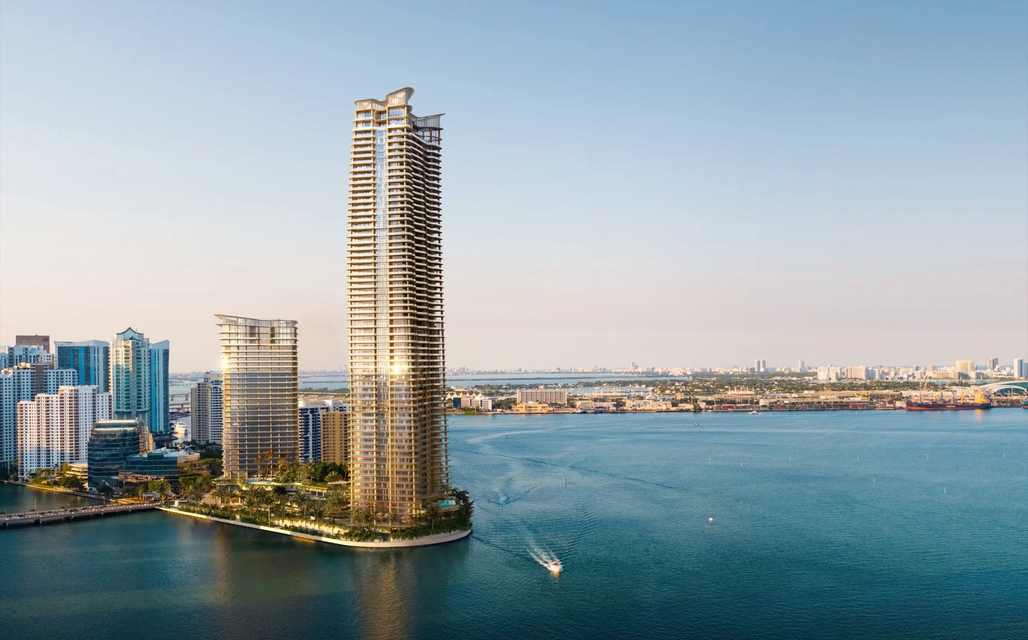 Tall modern skyscraper near a body of water with smaller buildings and a boat in the water.