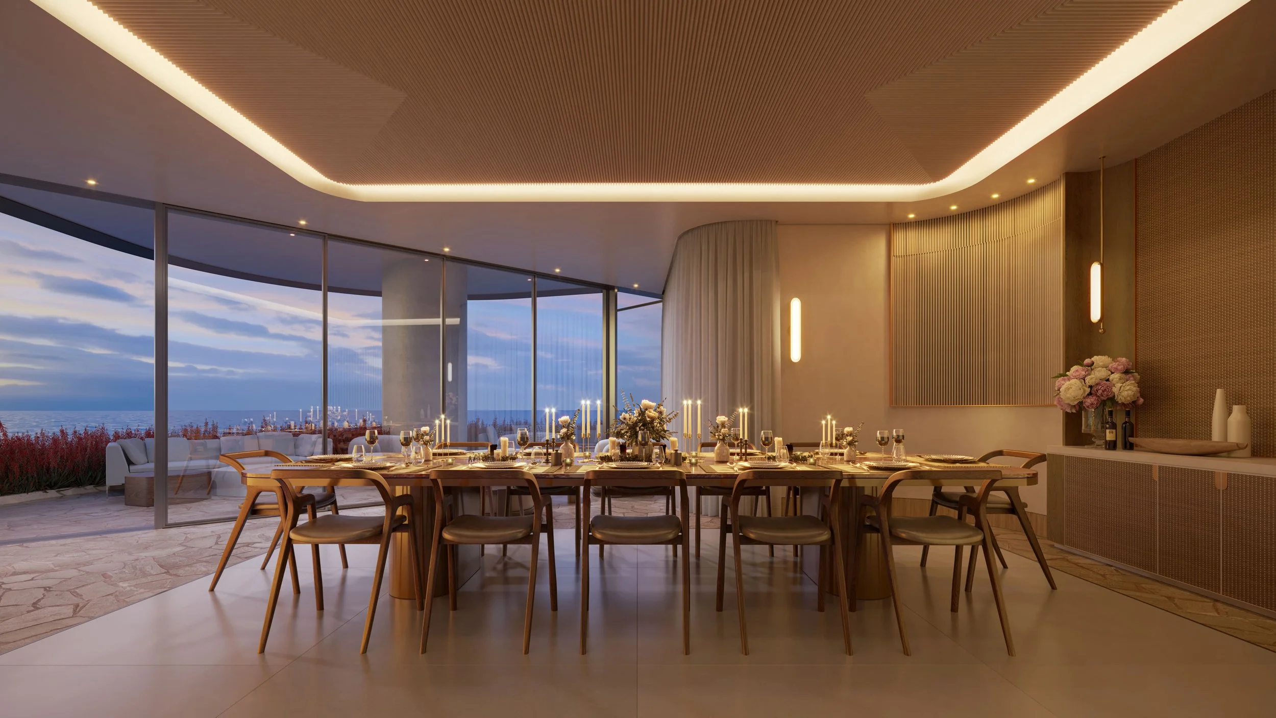 Elegant dining room with a large wooden table set with candles, glassware, and floral arrangements, overlooking an ocean view through floor-to-ceiling windows.