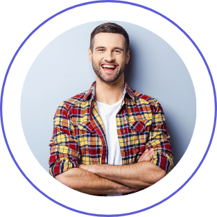 A smiling man with a beard, wearing a plaid shirt, standing against a light blue background with crossed arms.