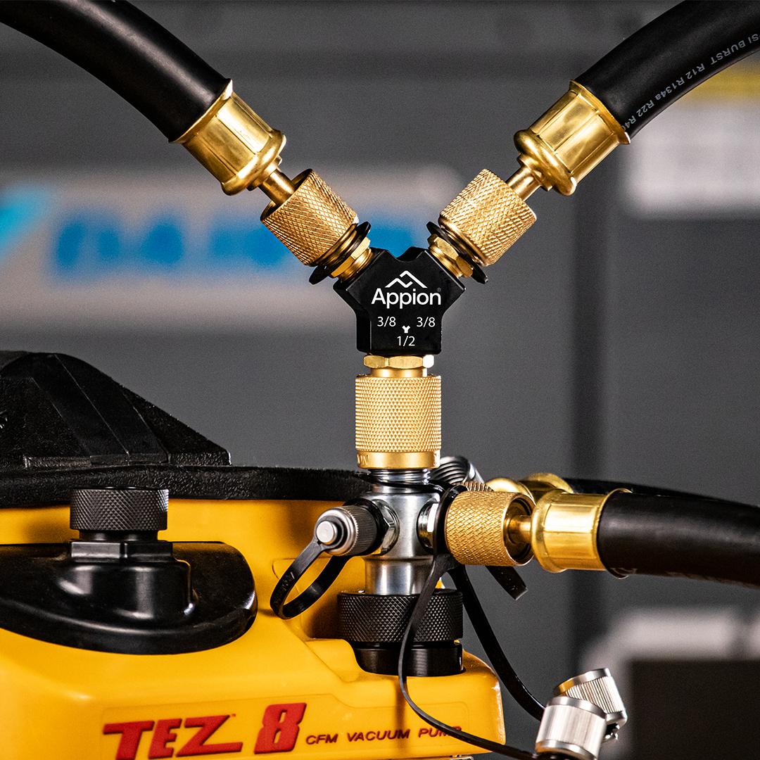 Close-up of a yellow TEZ 8 vacuum pump with black hoses connected to brass fittings.