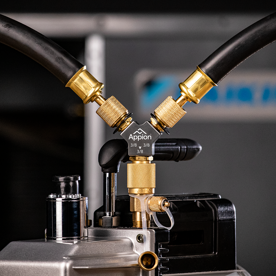 Close-up of a tattoo machine with black and gold components, connected by two flexible hoses, used for tattooing.